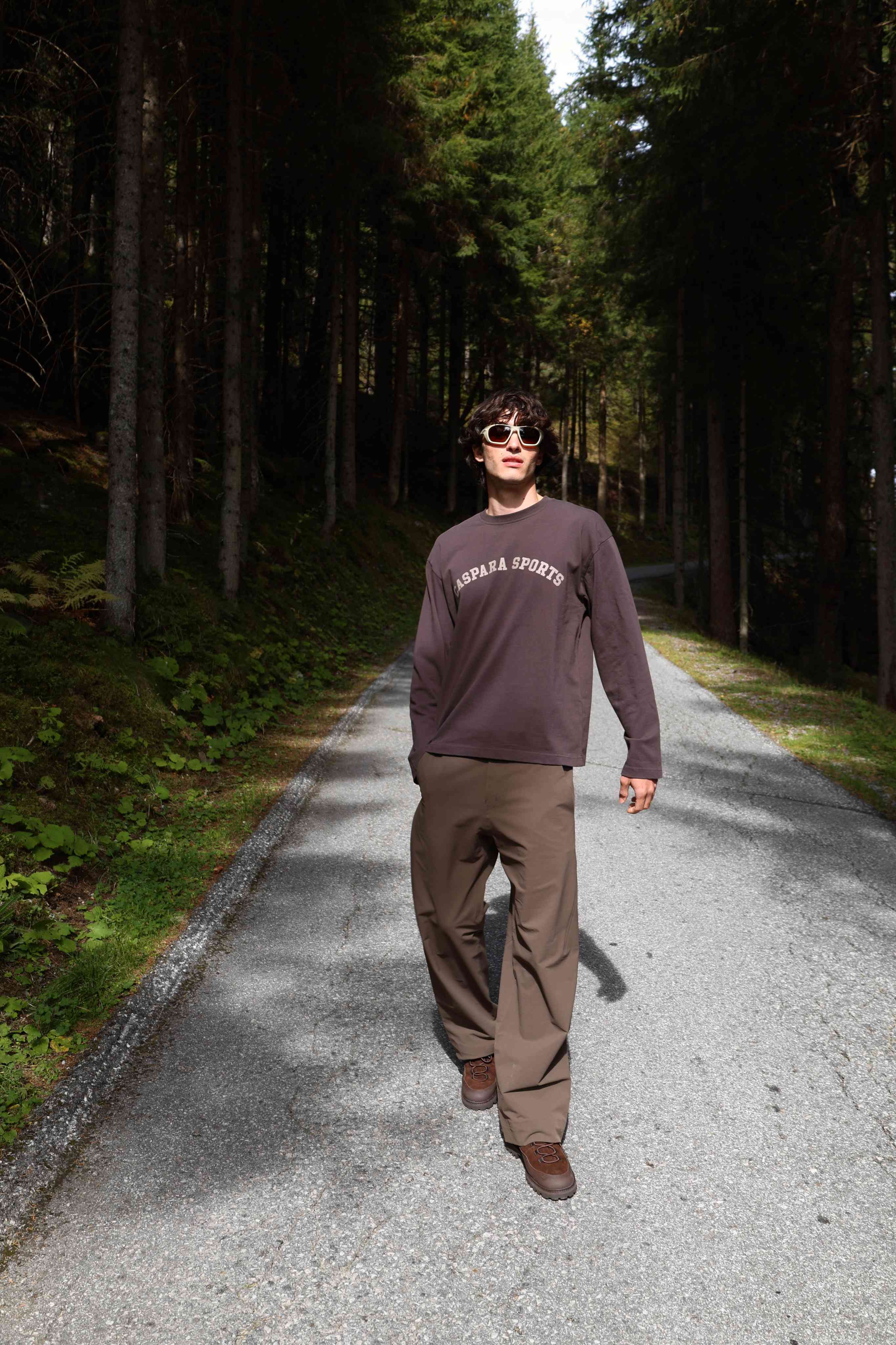 Man wearing an espresso CASPARA CS Signature long sleeve shirt walking along a forest road.