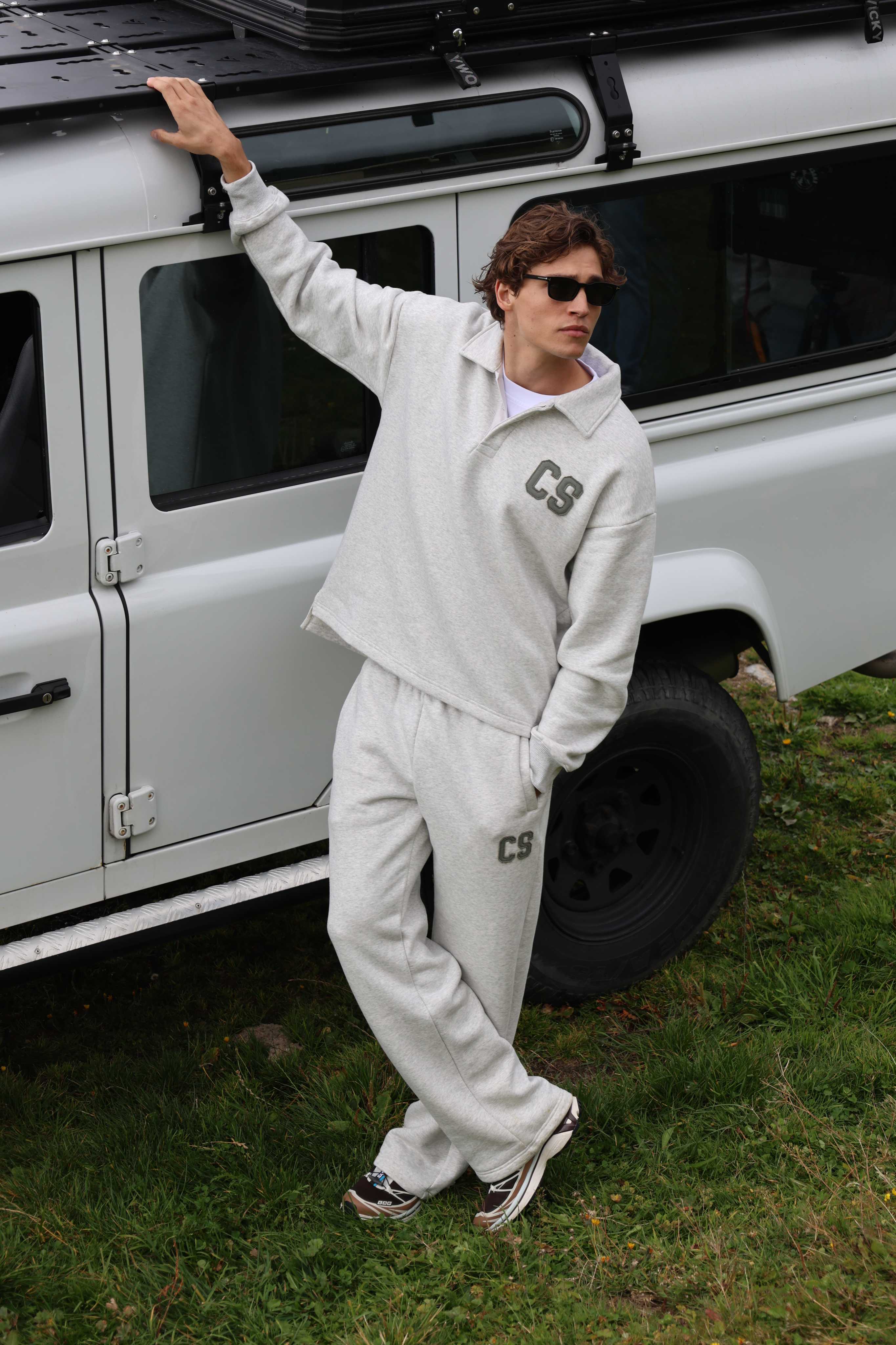 Man wearing grey melange CASPARA CS sweatpants and sweater leaning against an off-road vehicle.