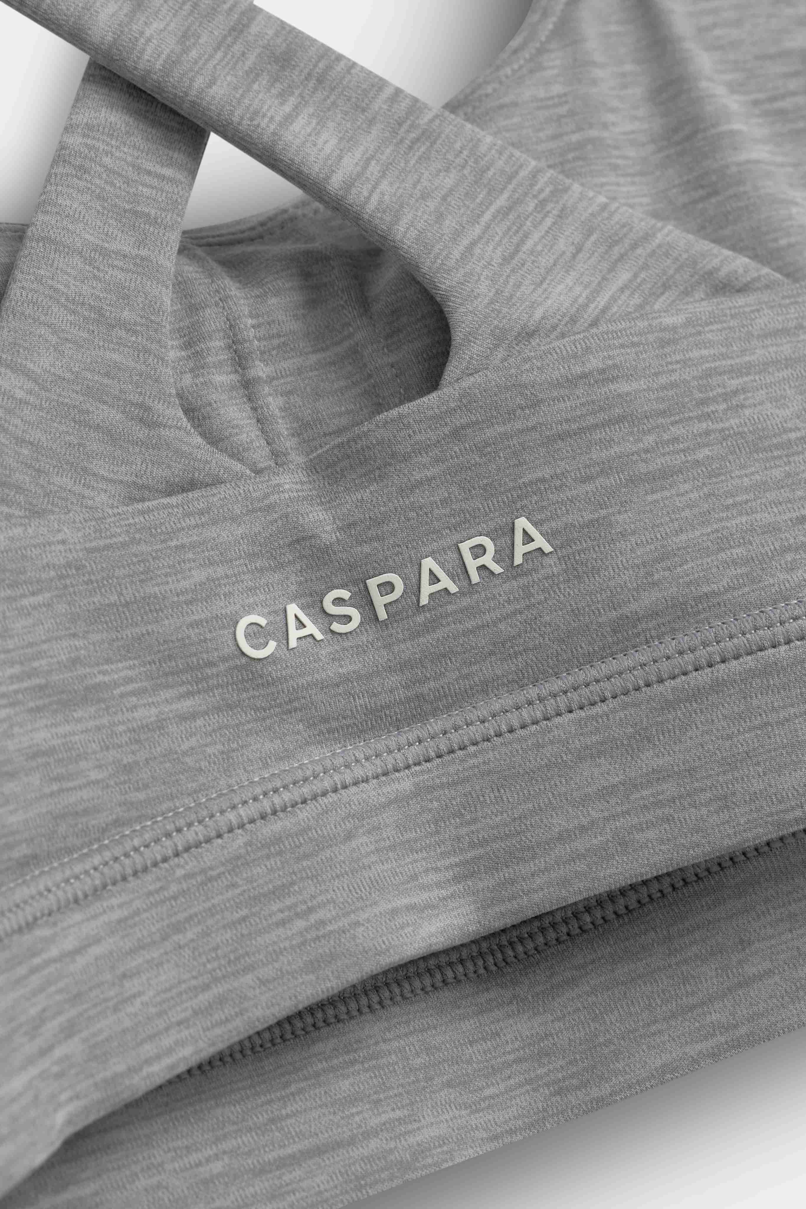Close-up of the grey melange CASPARA Cloudform crossback sports bra showing the logo and fabric texture.