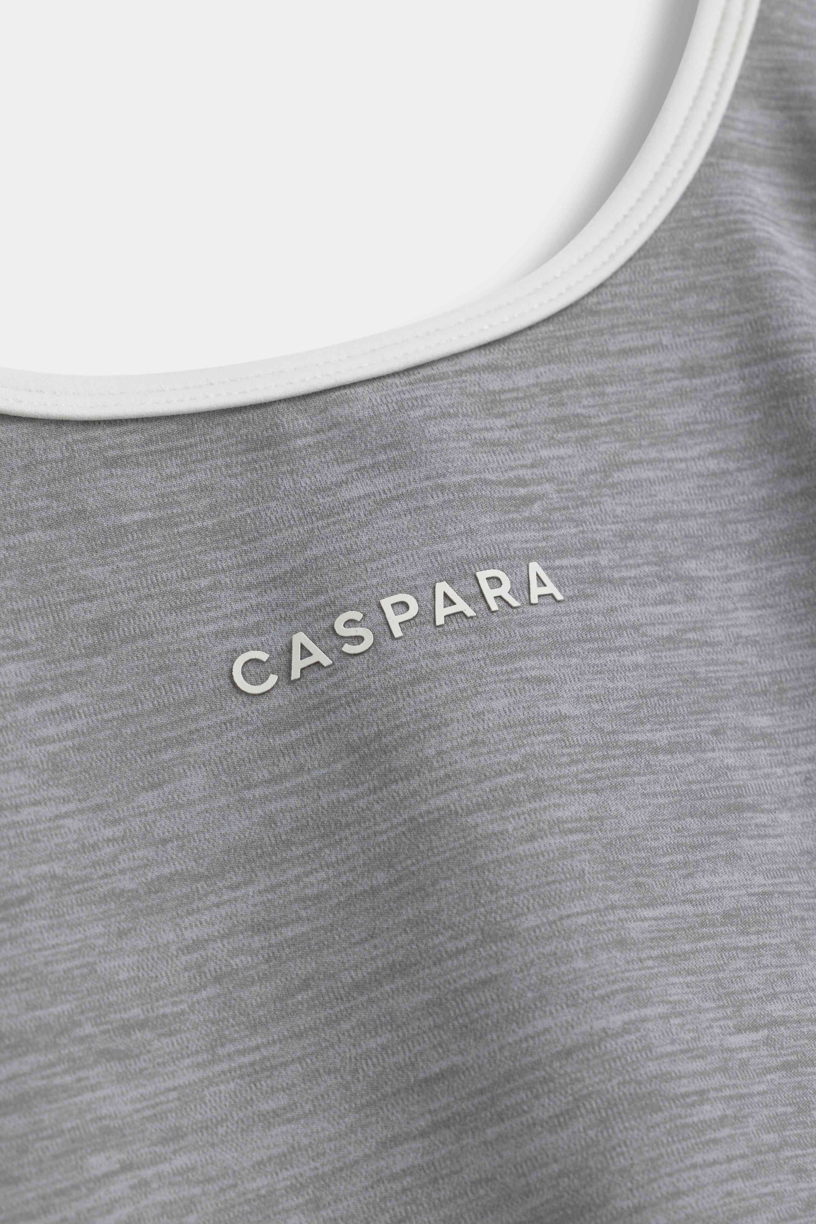 Close-up of the CASPARA logo and white trim on the grey melange Cloudform® square neck top.