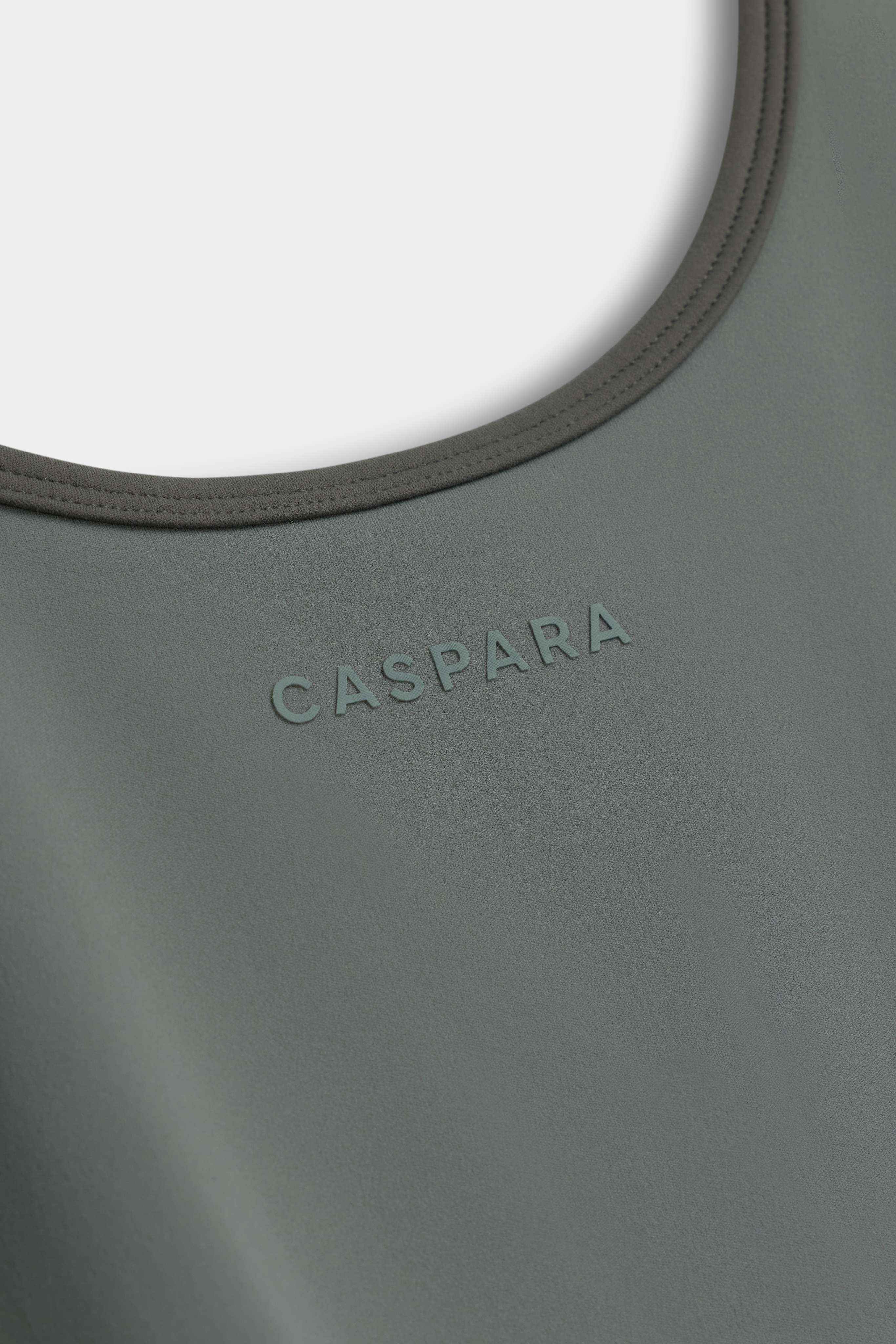 Close-up of the khaki CASPARA Cloudform top featuring the embossed logo and neckline trim.