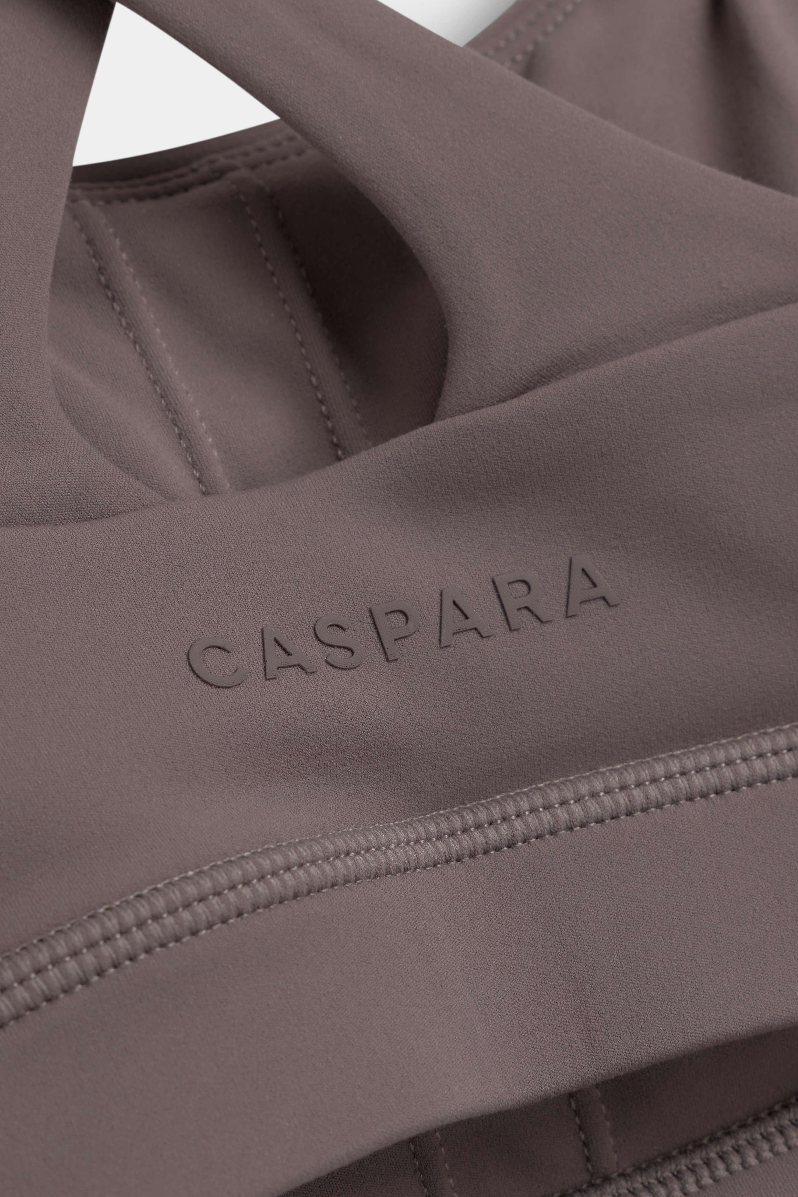 Close-up of the CASPARA logo and keyhole cutout on the walnut Cloudform crossback sports bra.