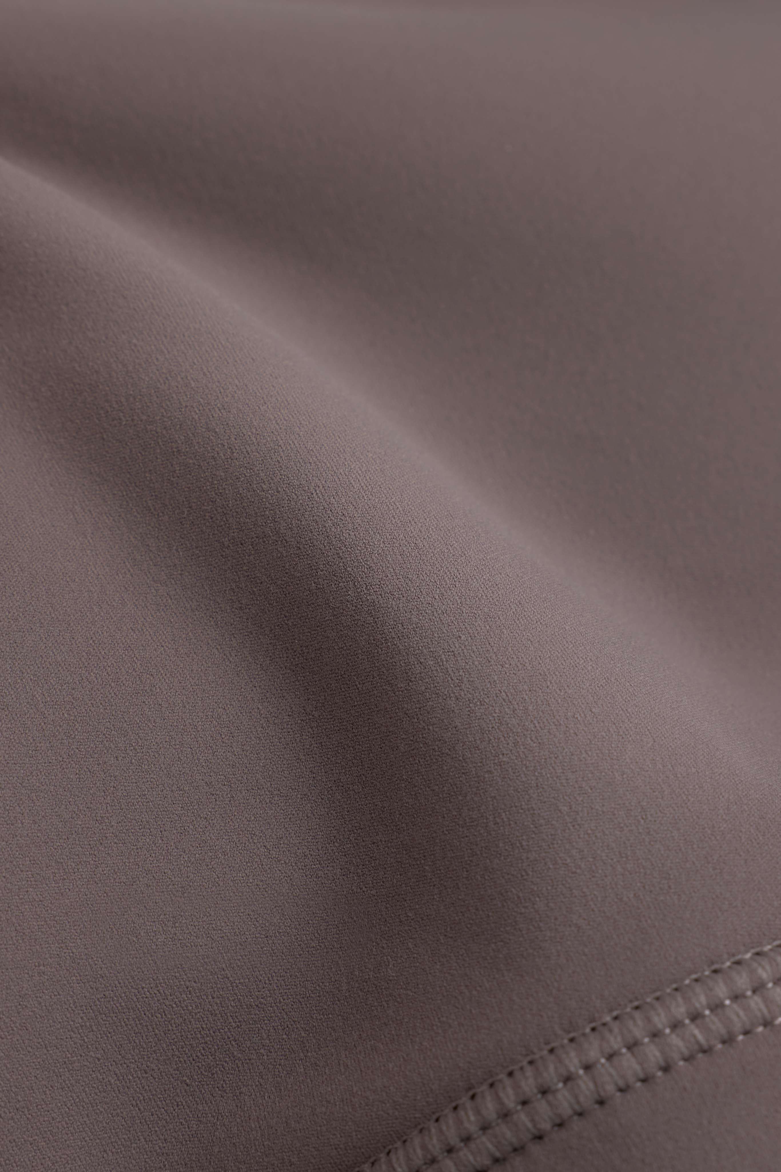 Close-up of the smooth walnut Cloudform fabric and stitched hem of the CASPARA crossback sports bra.