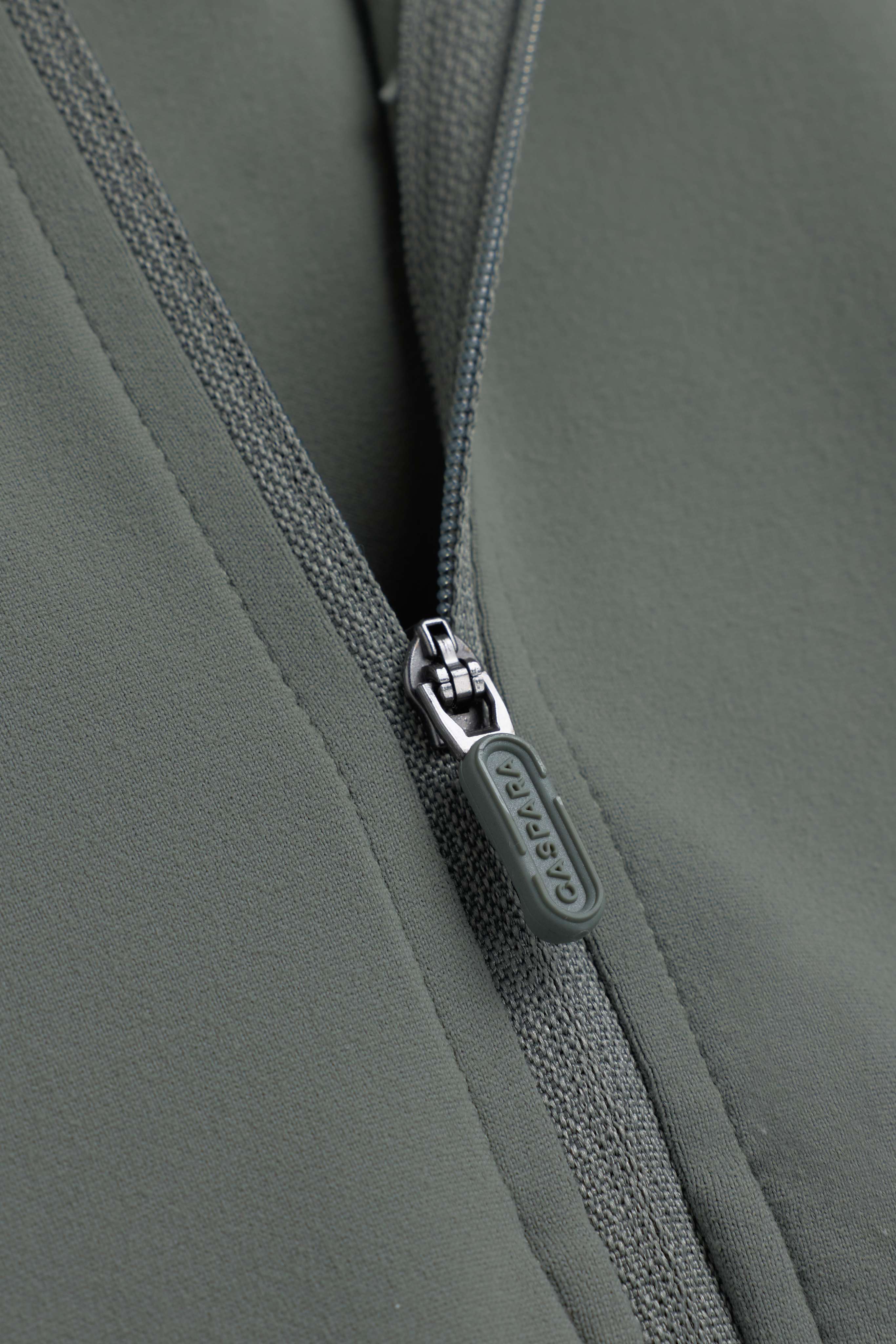 Close-up of the zipper with embossed CASPARA pull tab on the khaki Sculptluxe jacket.
