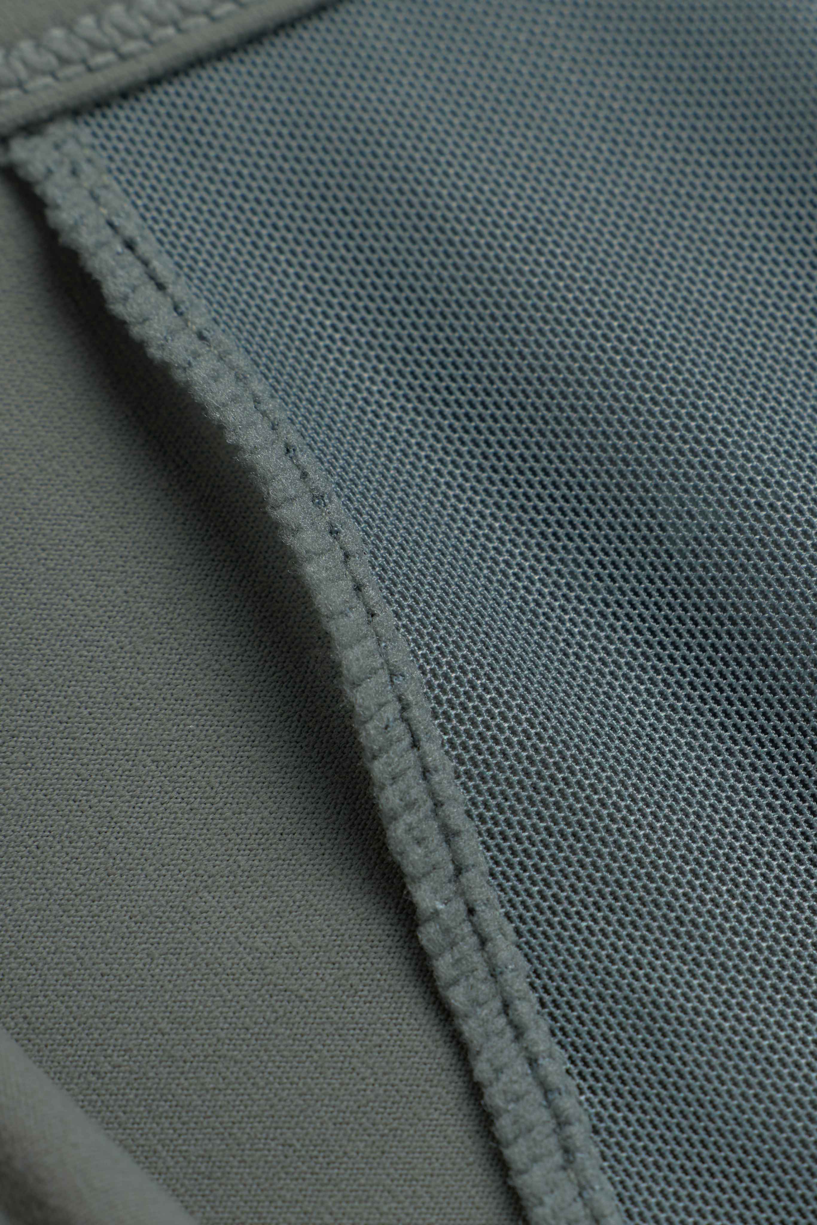 Close-up of the ventilated mesh fabric and seam on a khaki CASPARA Sculptluxe zip jacket.