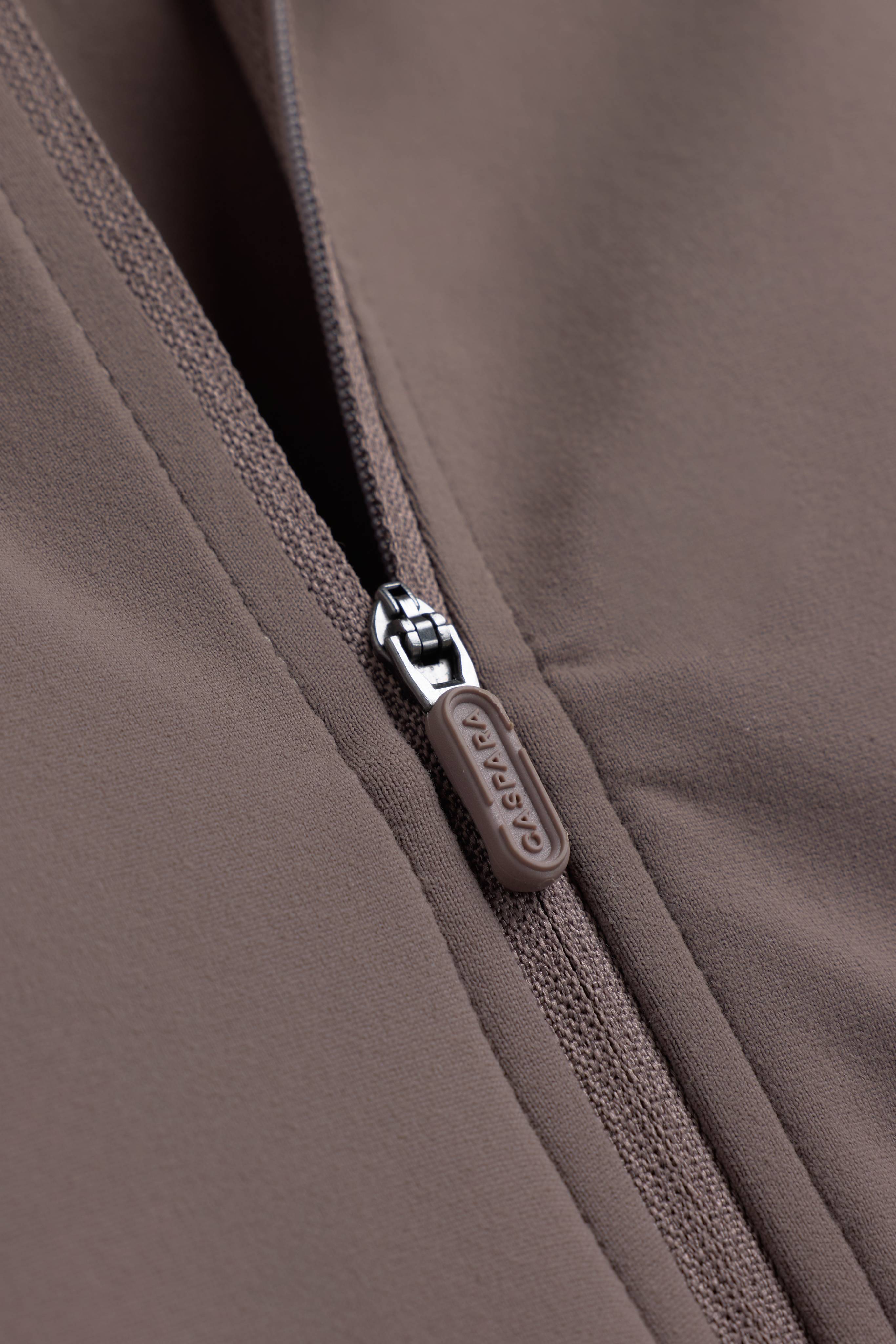 Close-up of the zipper pull on the walnut CASPARA Sculptluxe Zip Jacket.