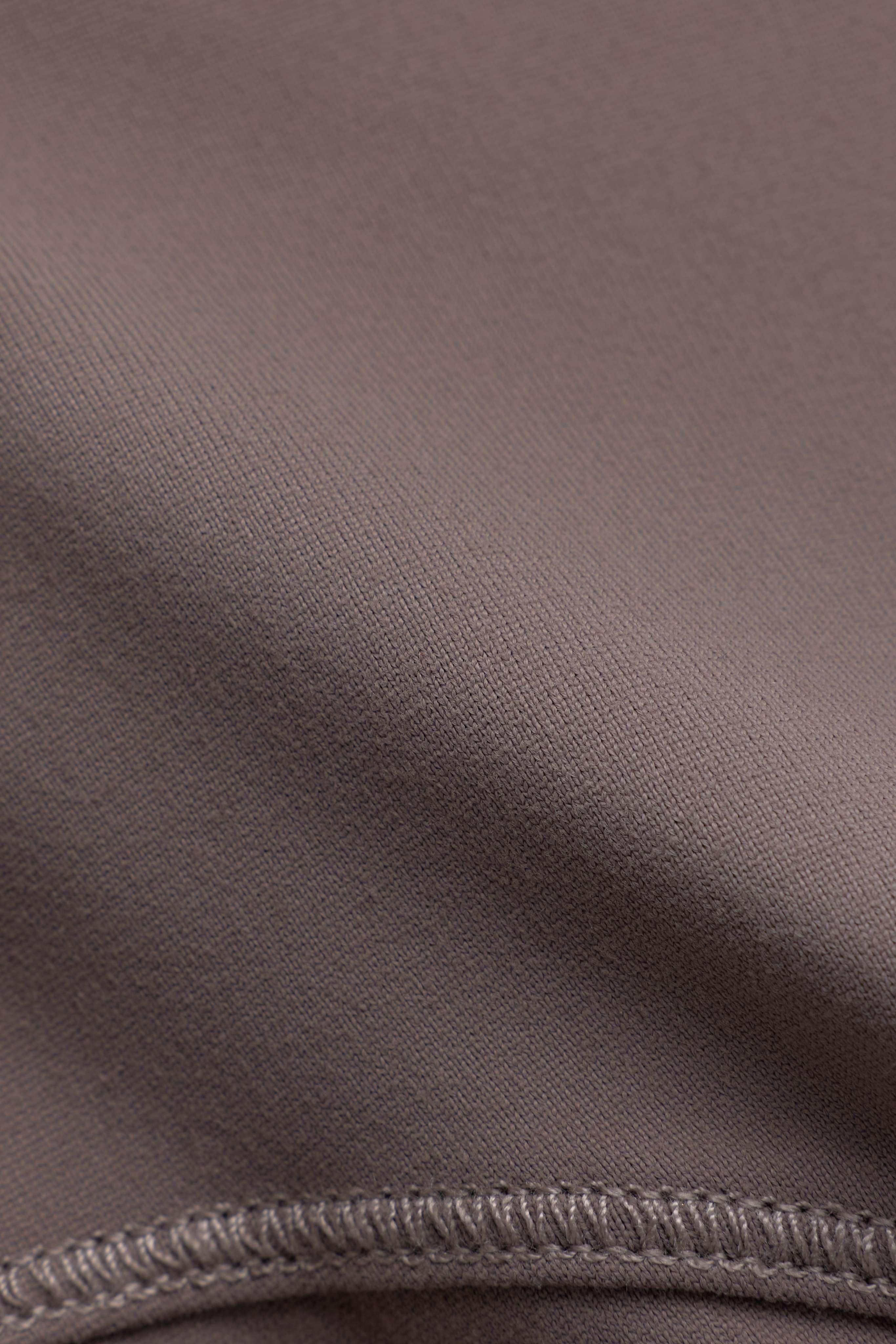Close-up of the walnut fabric texture and stitched seam on the CASPARA Sculptluxe jacket.
