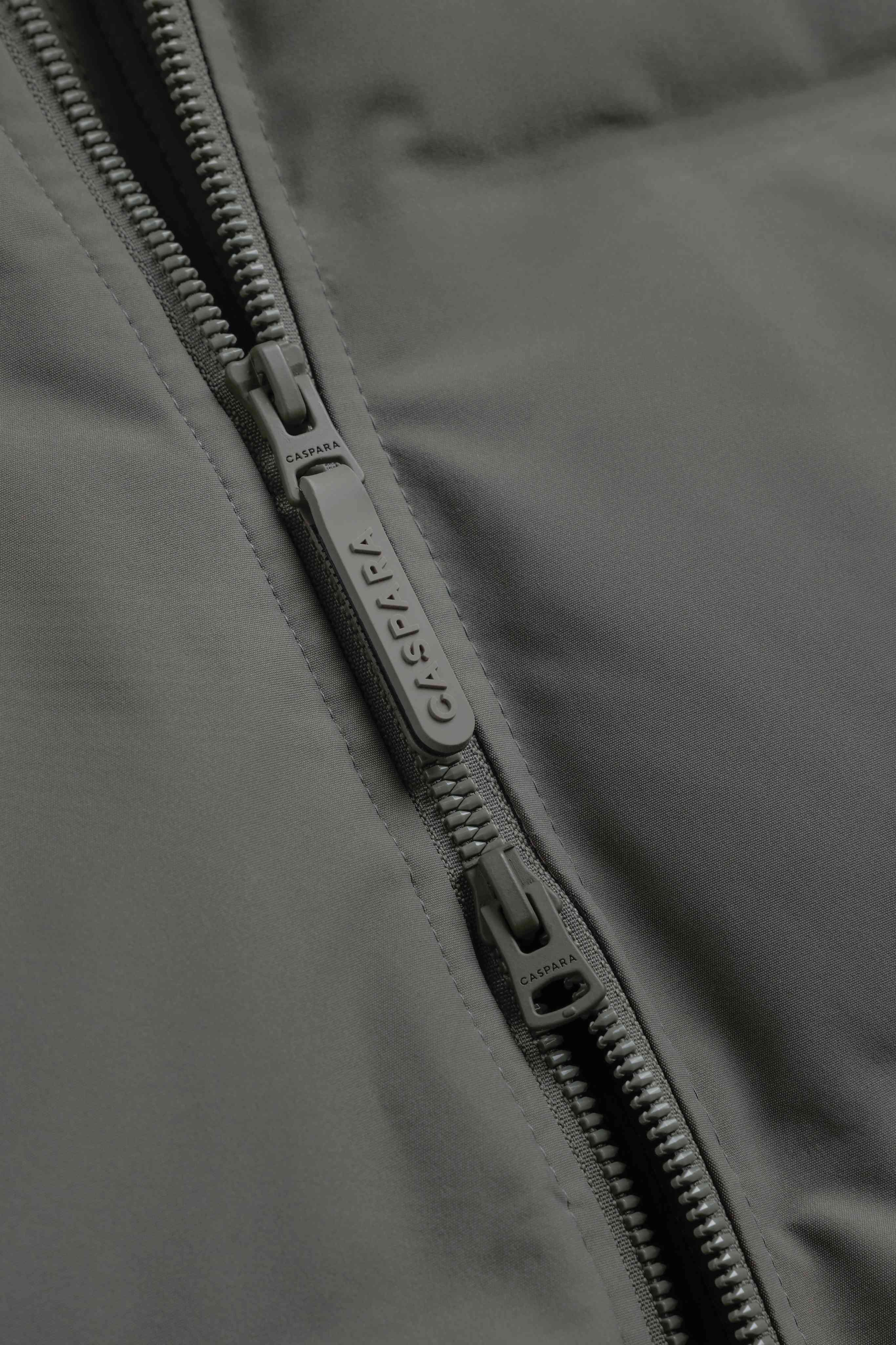 Close-up of the two-way front zipper pull on the khaki CASPARA Boreal Puffer Jacket.