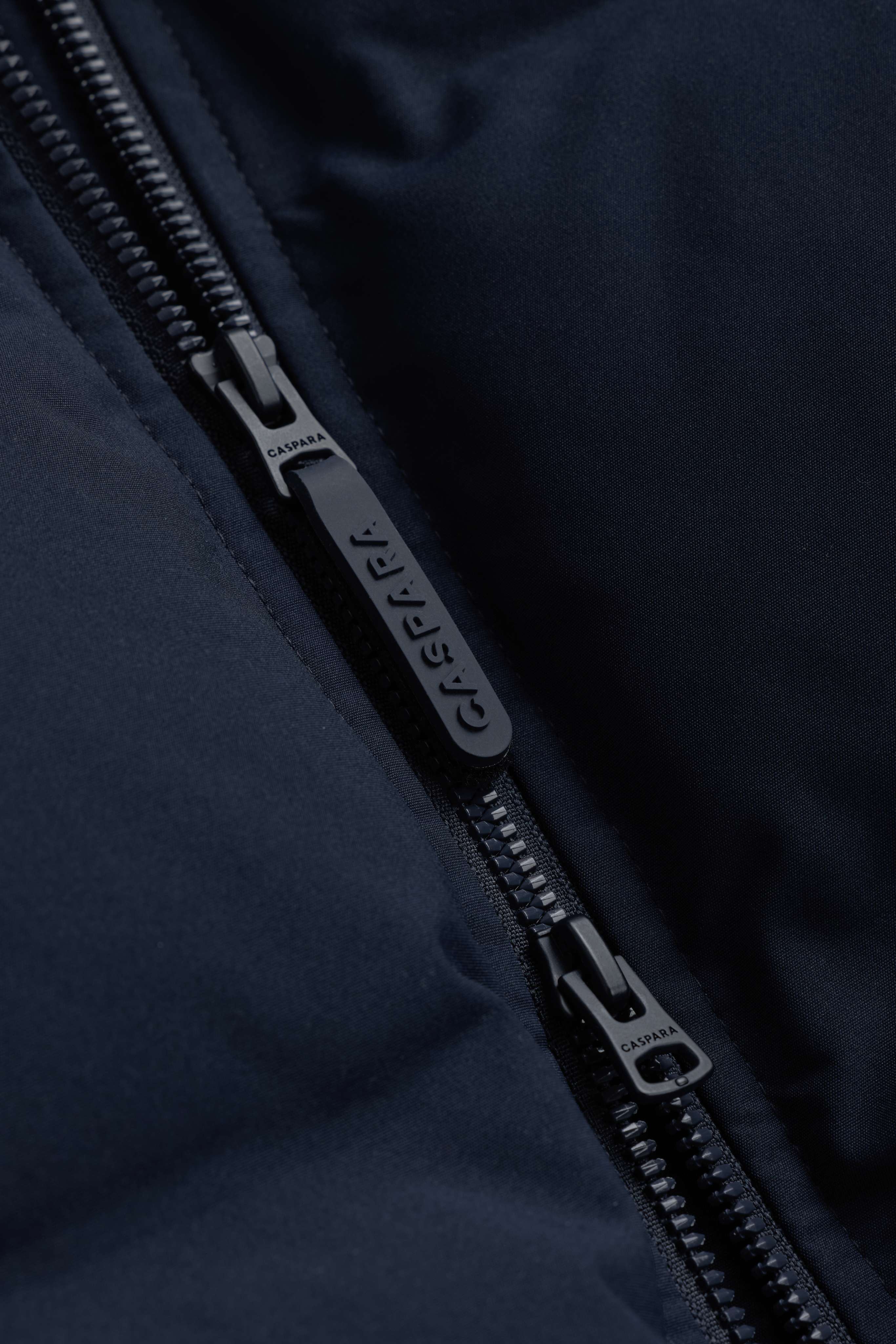 Close-up of the two-way front zipper on the navy CASPARA Aurora Puffer Jacket.