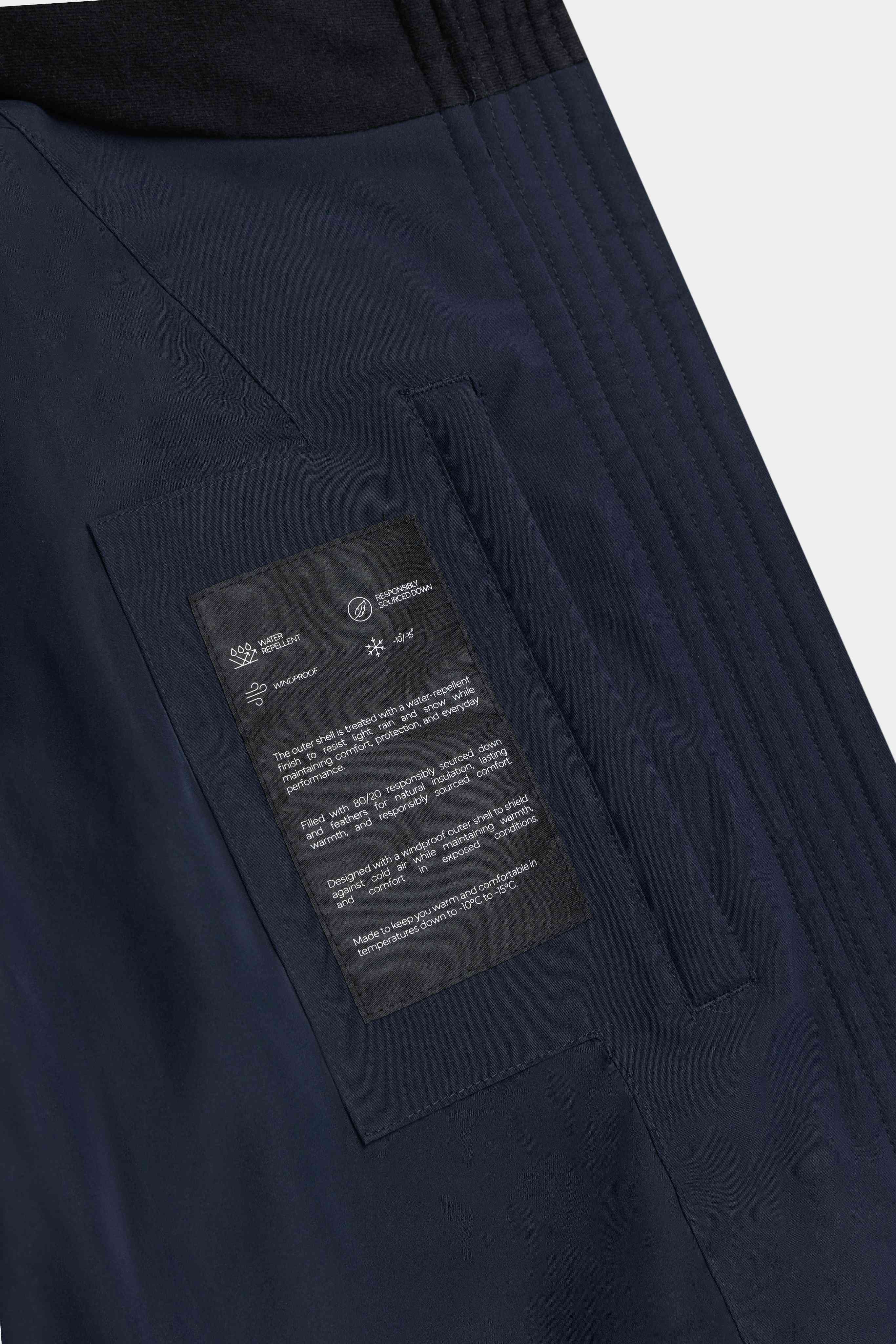 Interior feature label and inside pocket detail on the navy CASPARA Aurora puffer jacket.