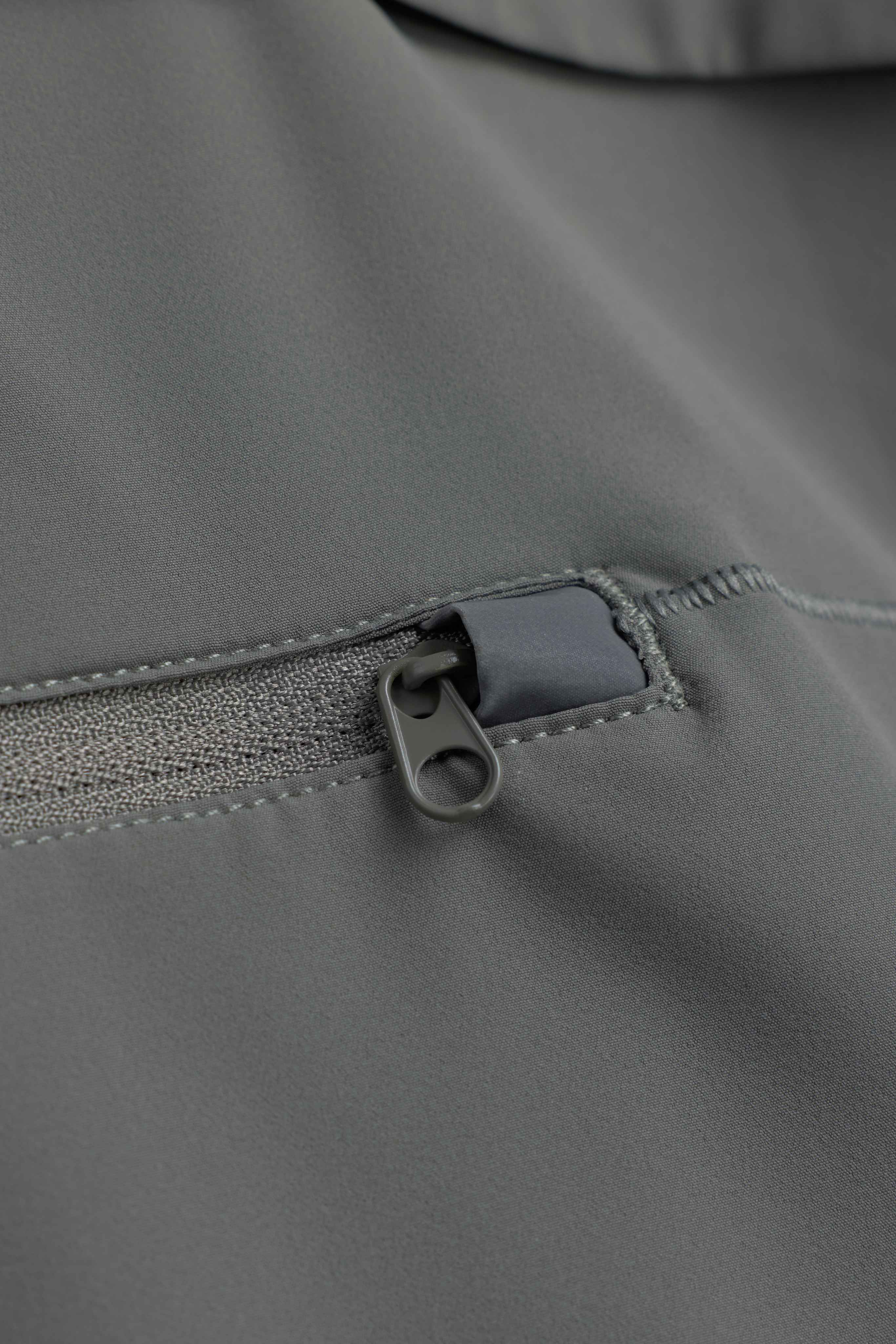 Close-up of the zipper pocket on the khaki CASPARA Windluxe jacket.