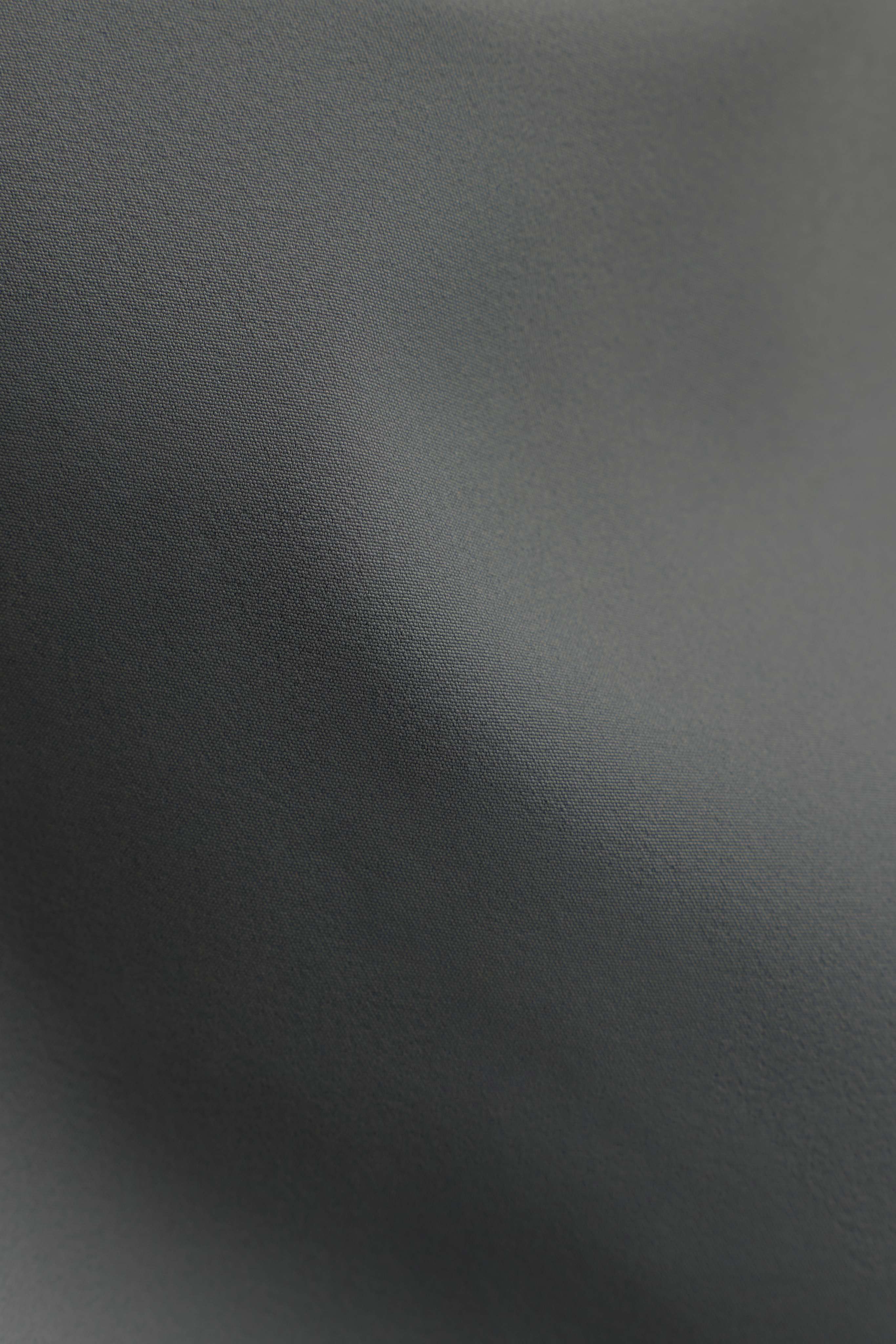 Close-up of the smooth, woven khaki fabric of the CASPARA Windluxe jacket.