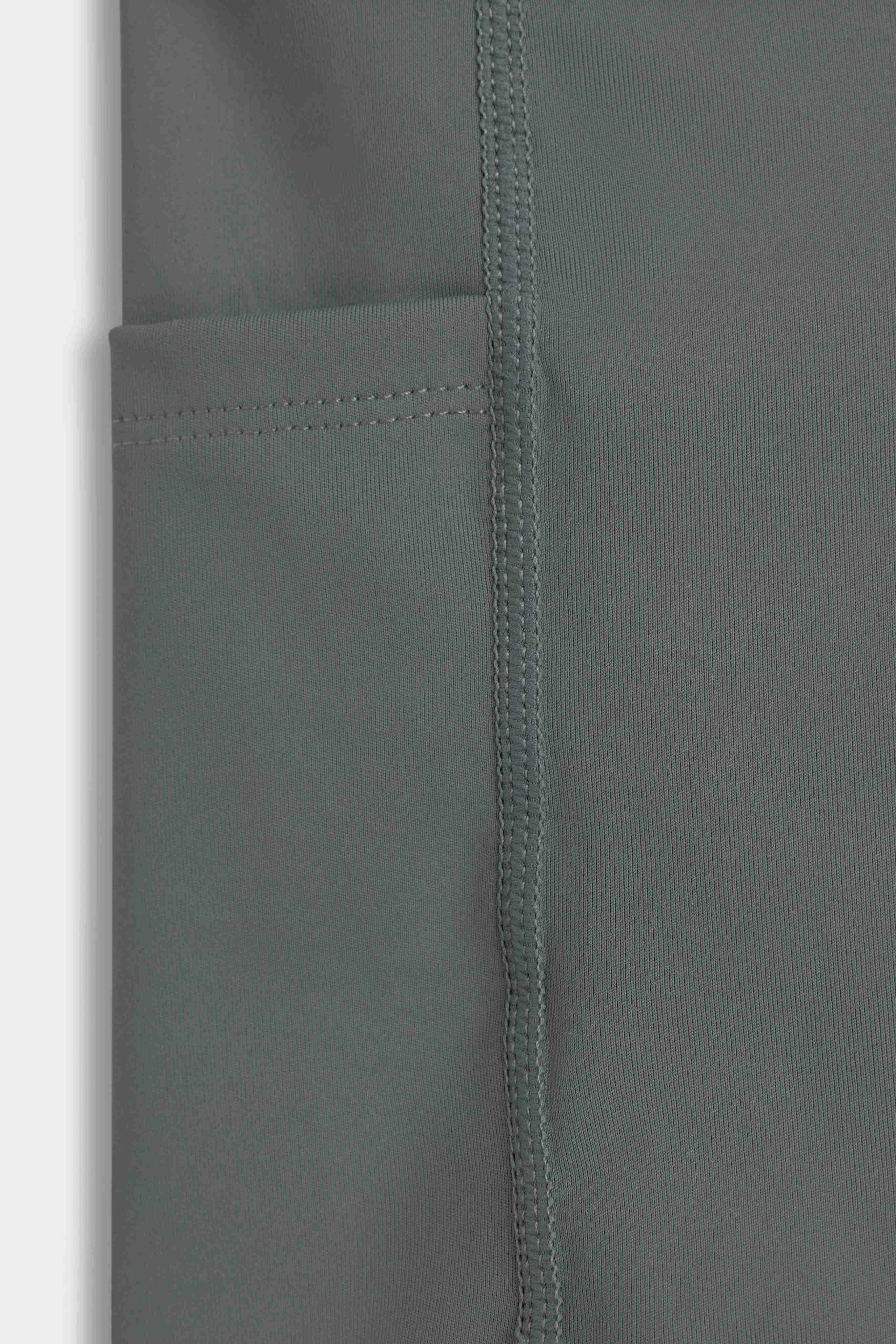Close-up of the side pocket and flatlock seams on khaki CASPARA Aerluxe shorts.