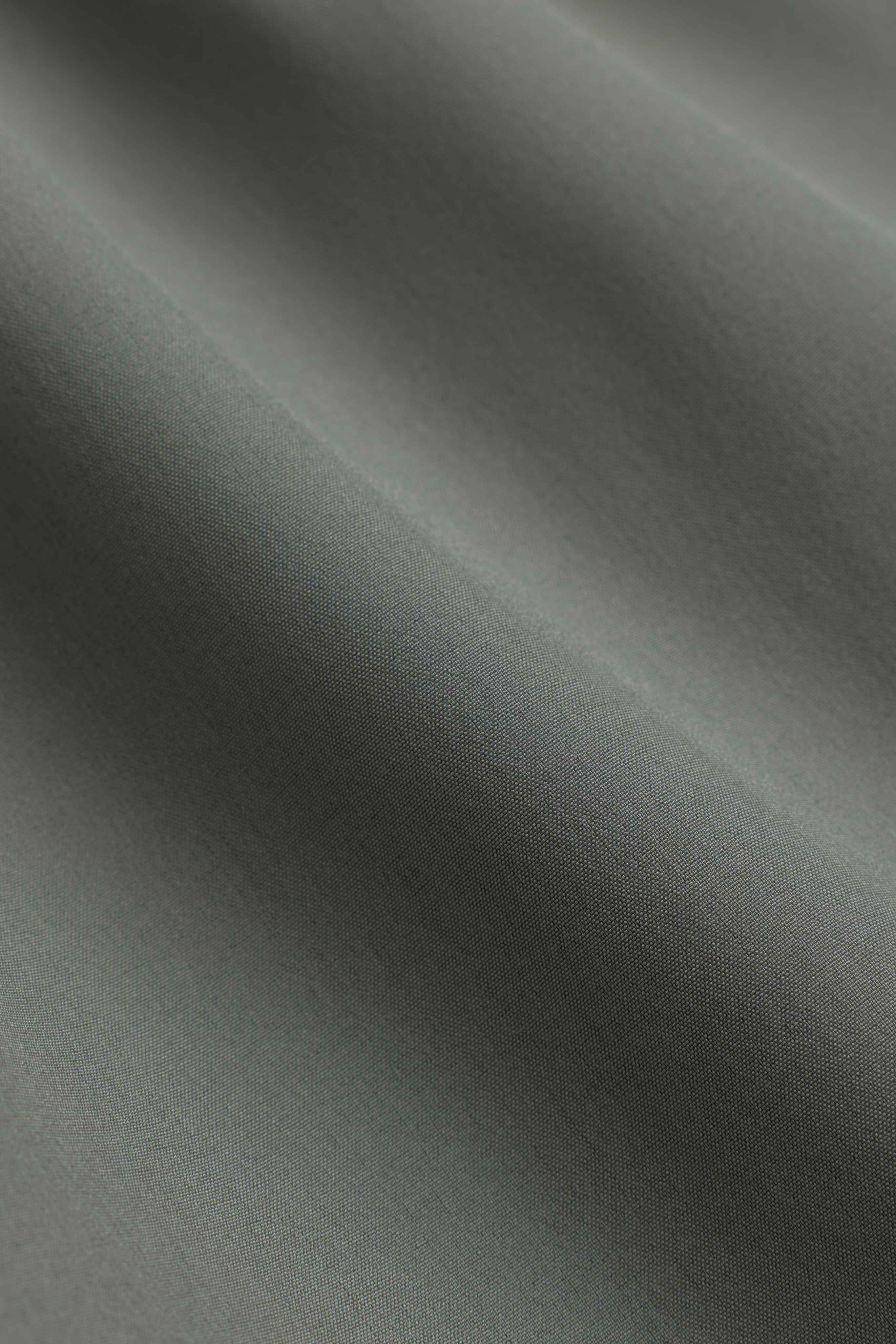 Close-up of the smooth khaki technical fabric of the CASPARA Aerluxe shorts.