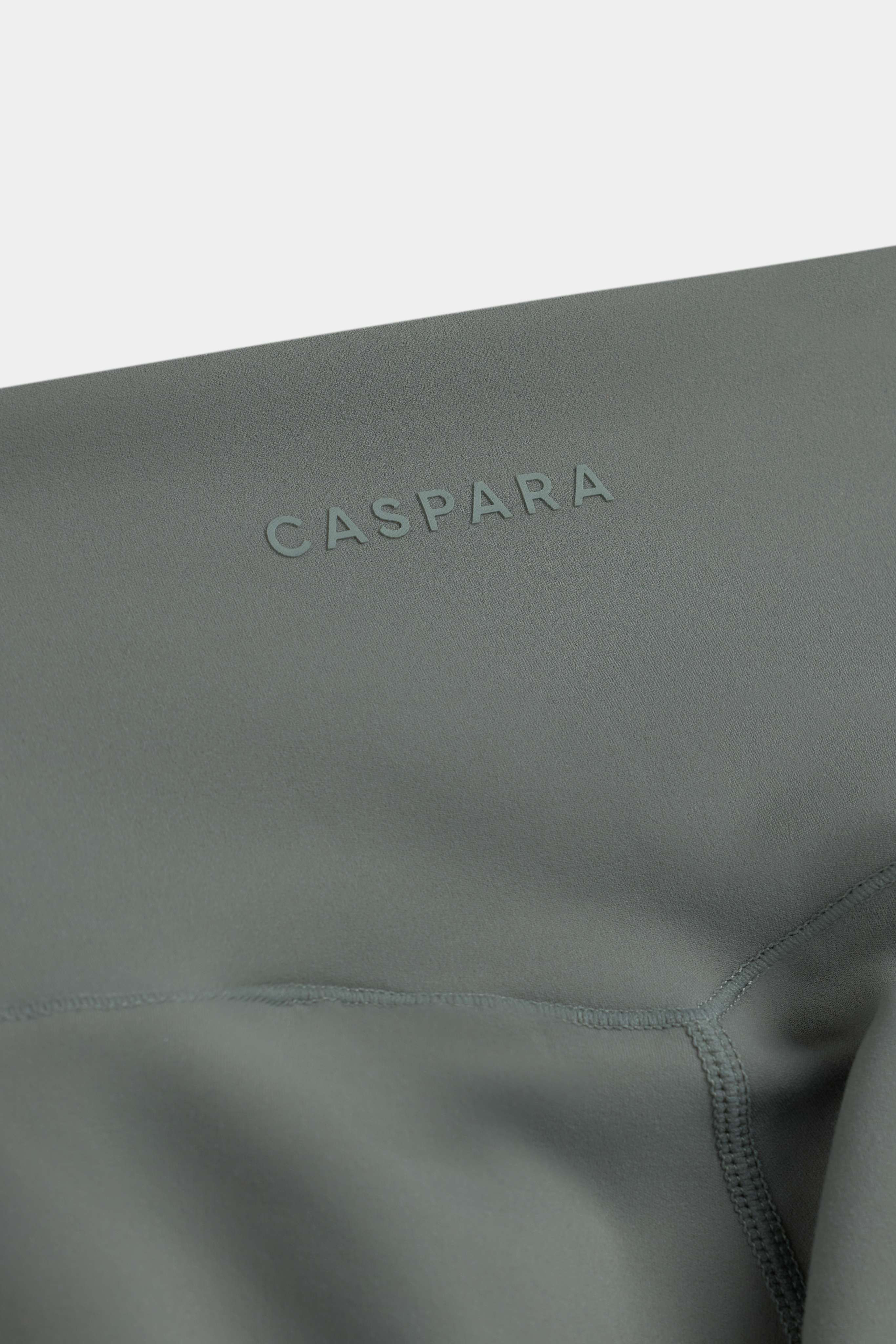 Close-up of the khaki CASPARA Cloudform capri tights showing the tonal logo on the waistband.