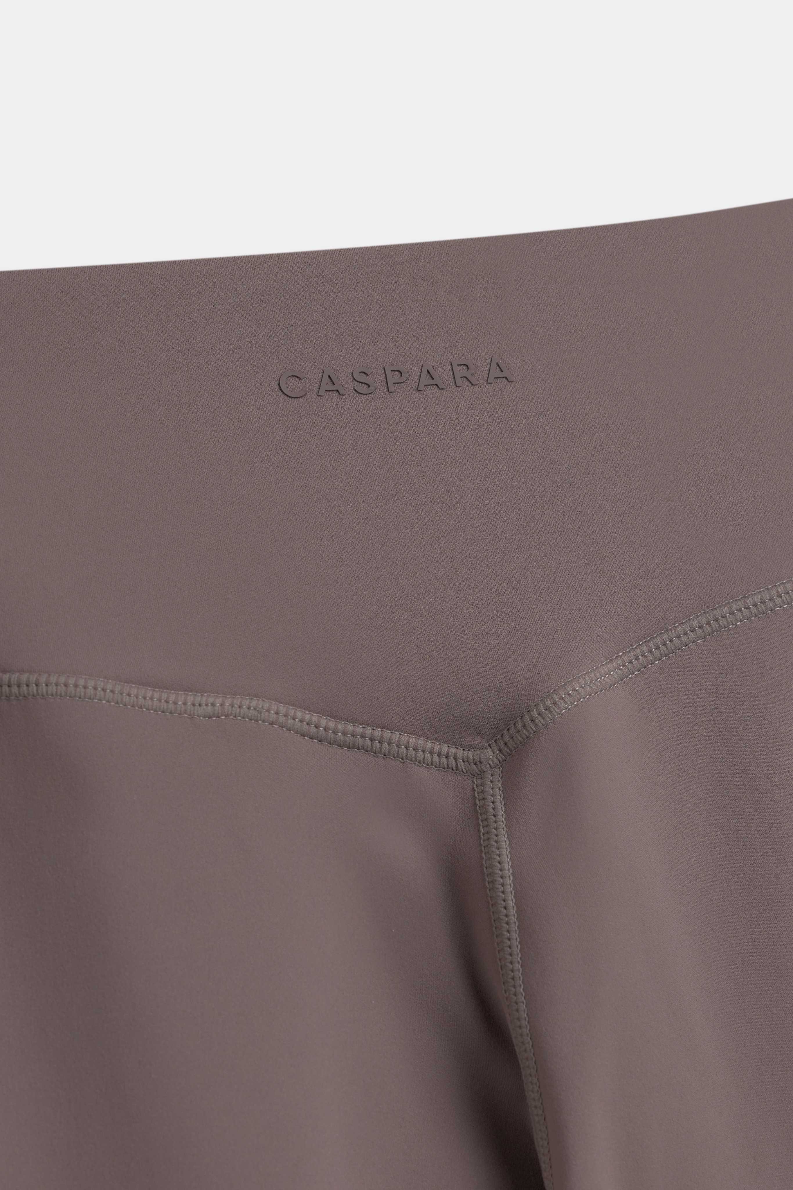 Close-up of the back waistband on walnut CASPARA Cloudform yoga pants showing the logo and V-seam.