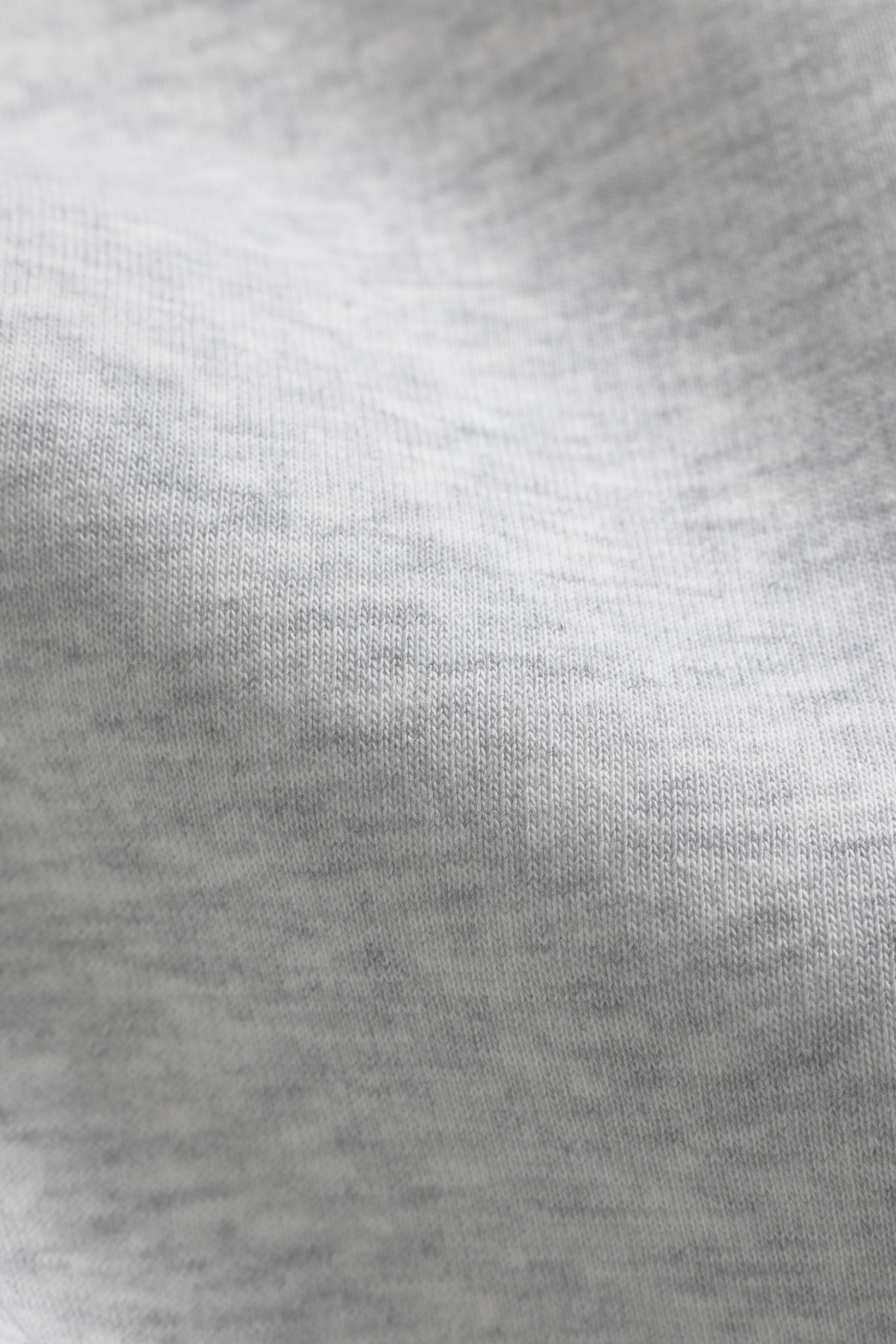 Close-up of the soft grey melange fabric on a CASPARA CS crewneck.