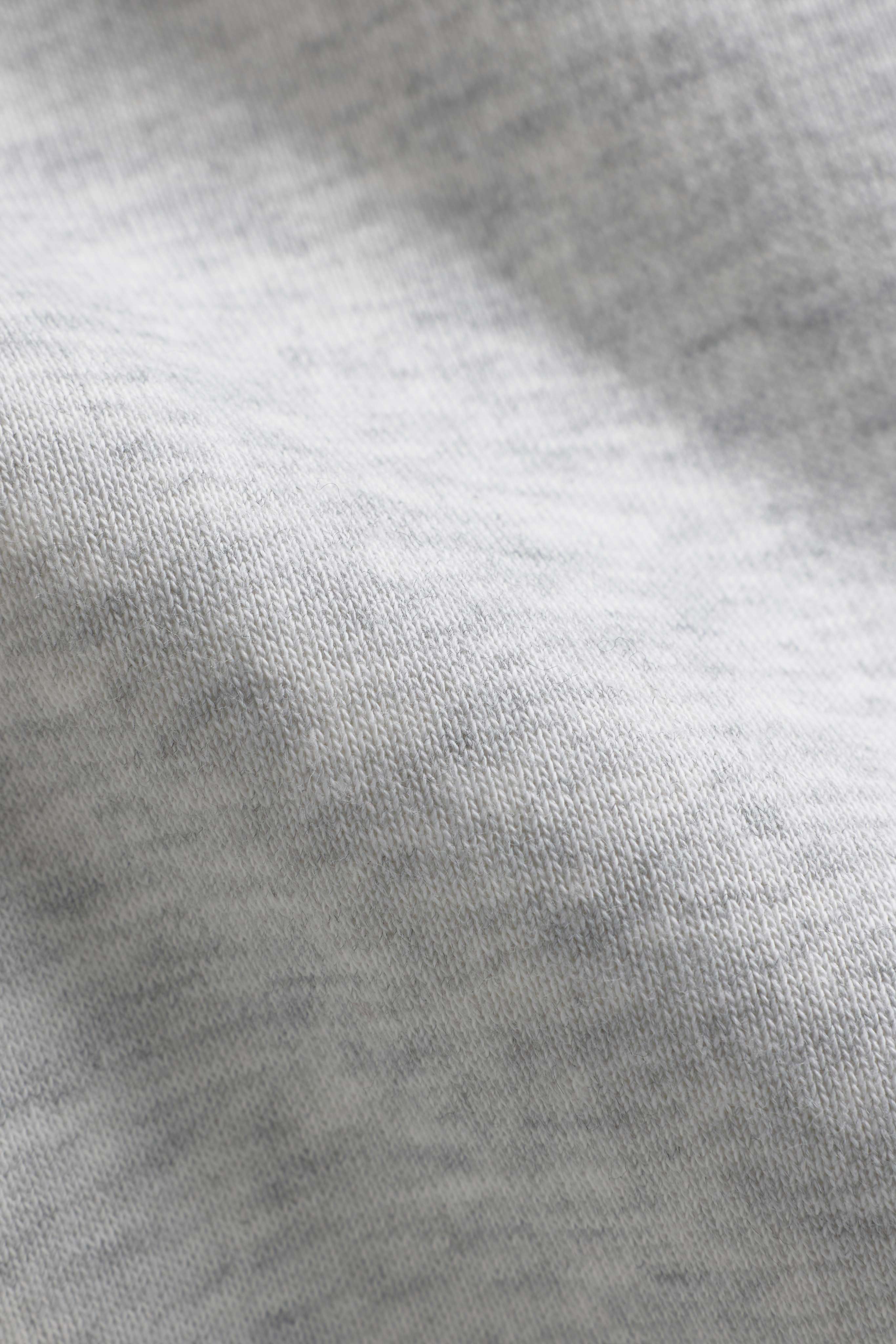 Close-up of the grey melange knit fabric texture on a CASPARA CS hoodie.