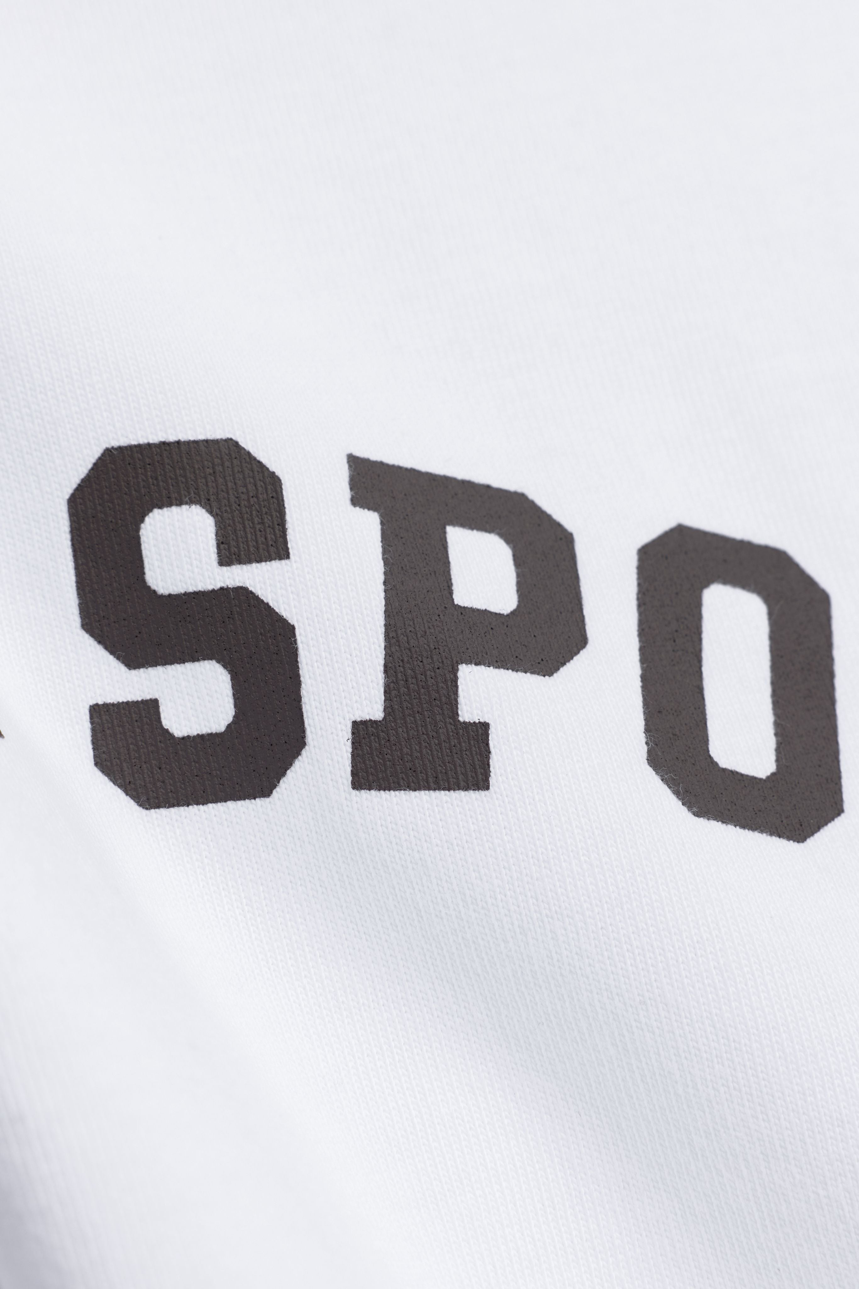 Close-up of espresso printed lettering on the white CASPARA CS Signature long sleeve.