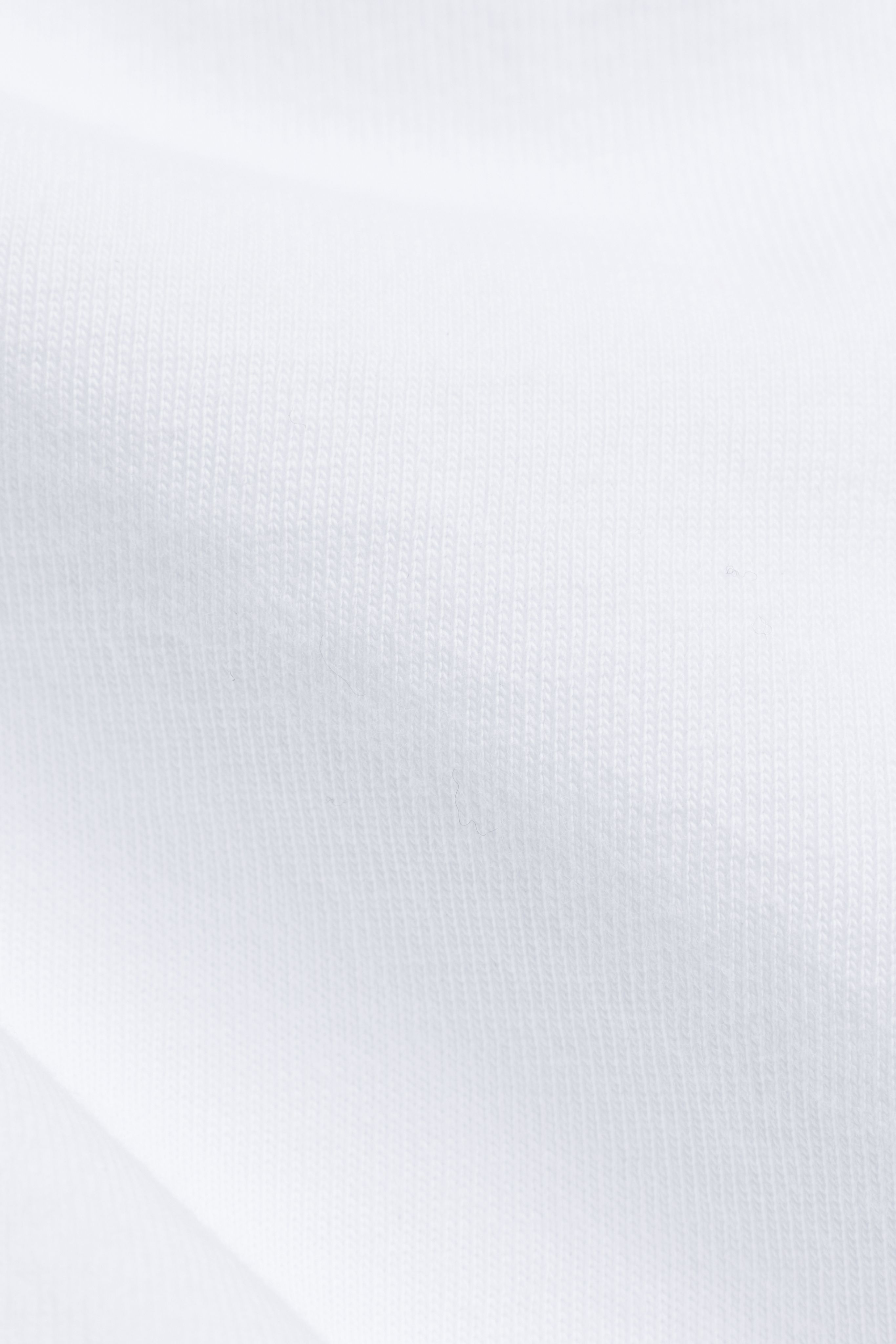 Close-up view of the white cotton fabric on a CASPARA long sleeve shirt.