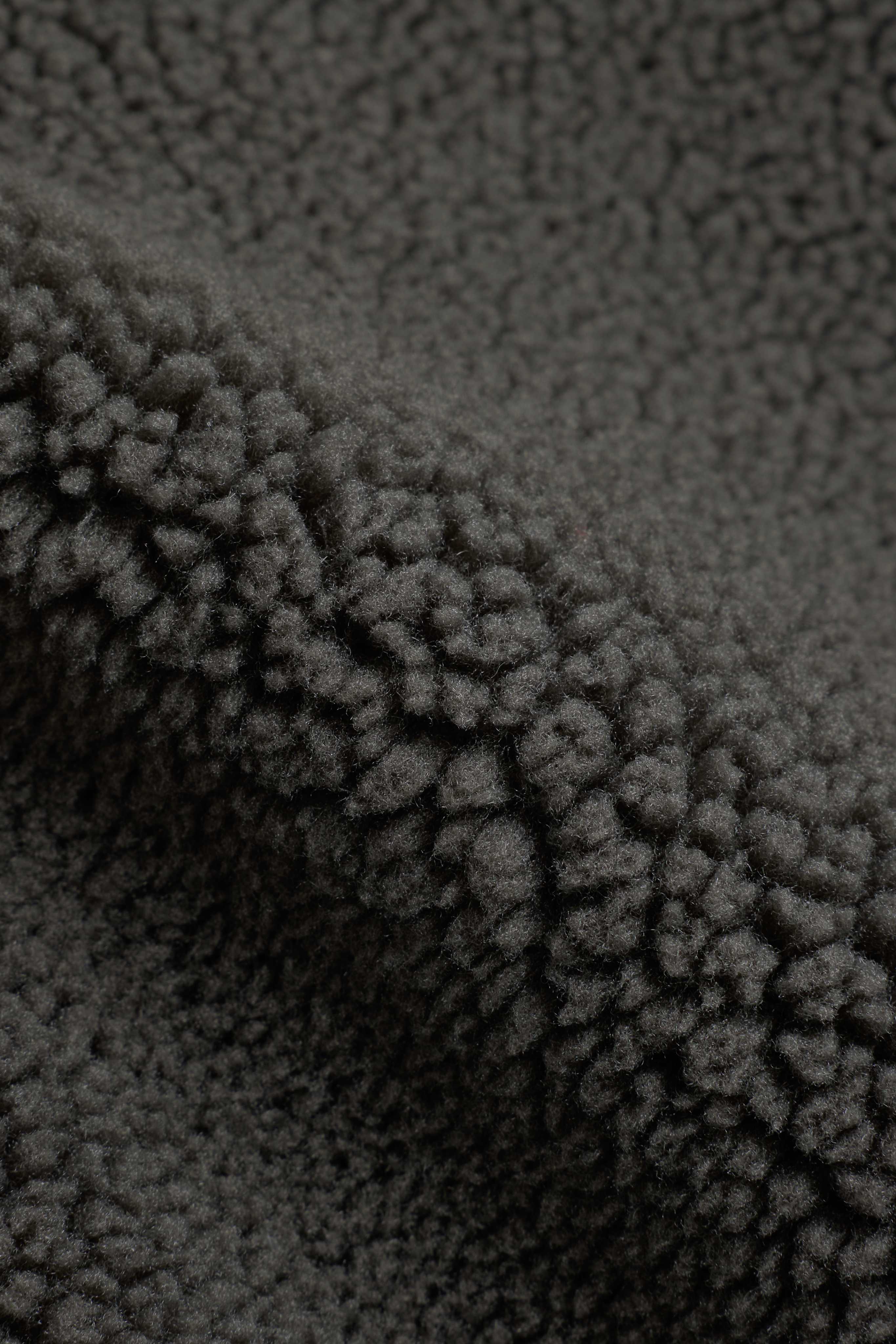 Close-up of textured khaki fleece fabric on a CASPARA Cloudfleece vest.