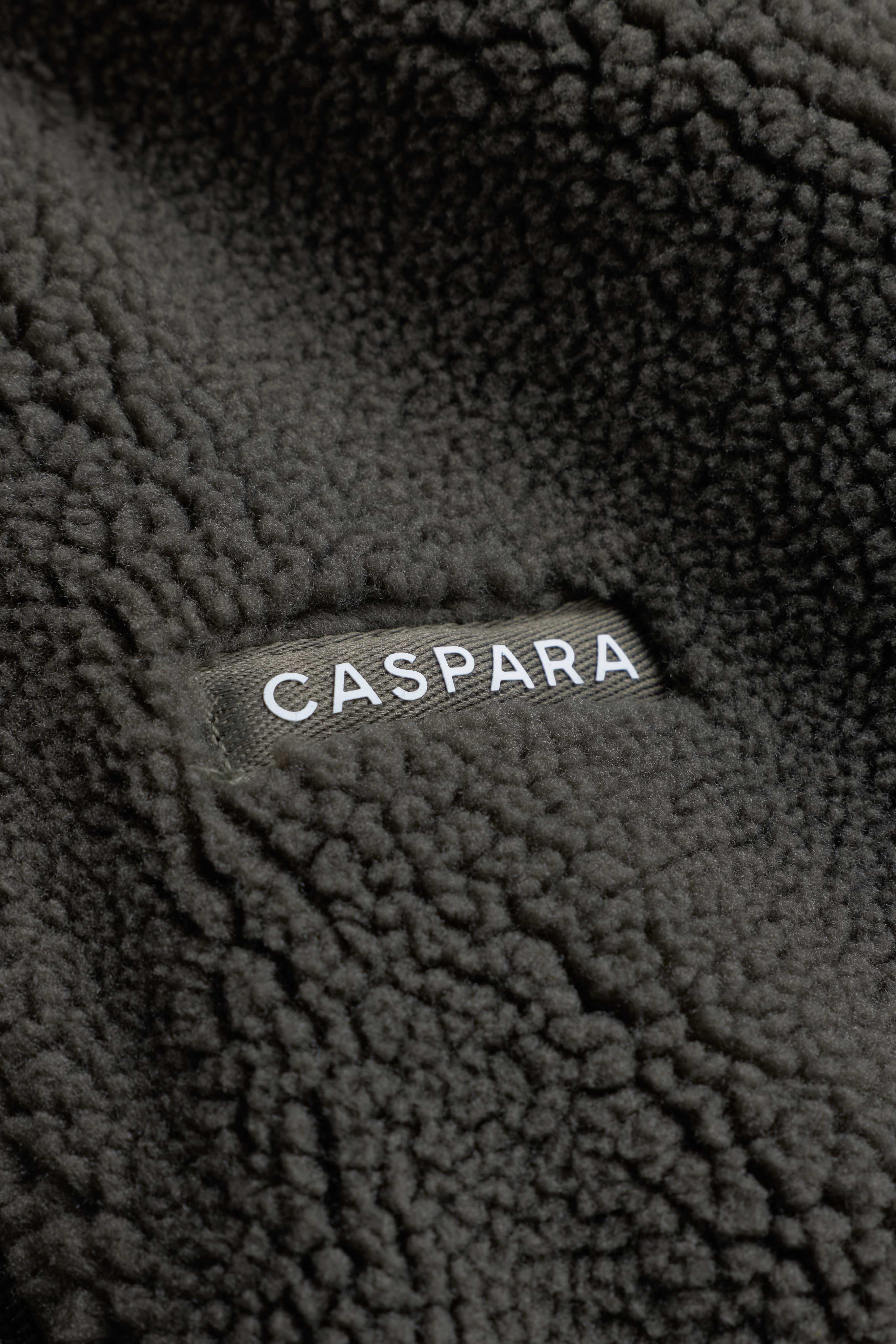 Close-up view of the textured khaki fleece with a woven CASPARA logo label.