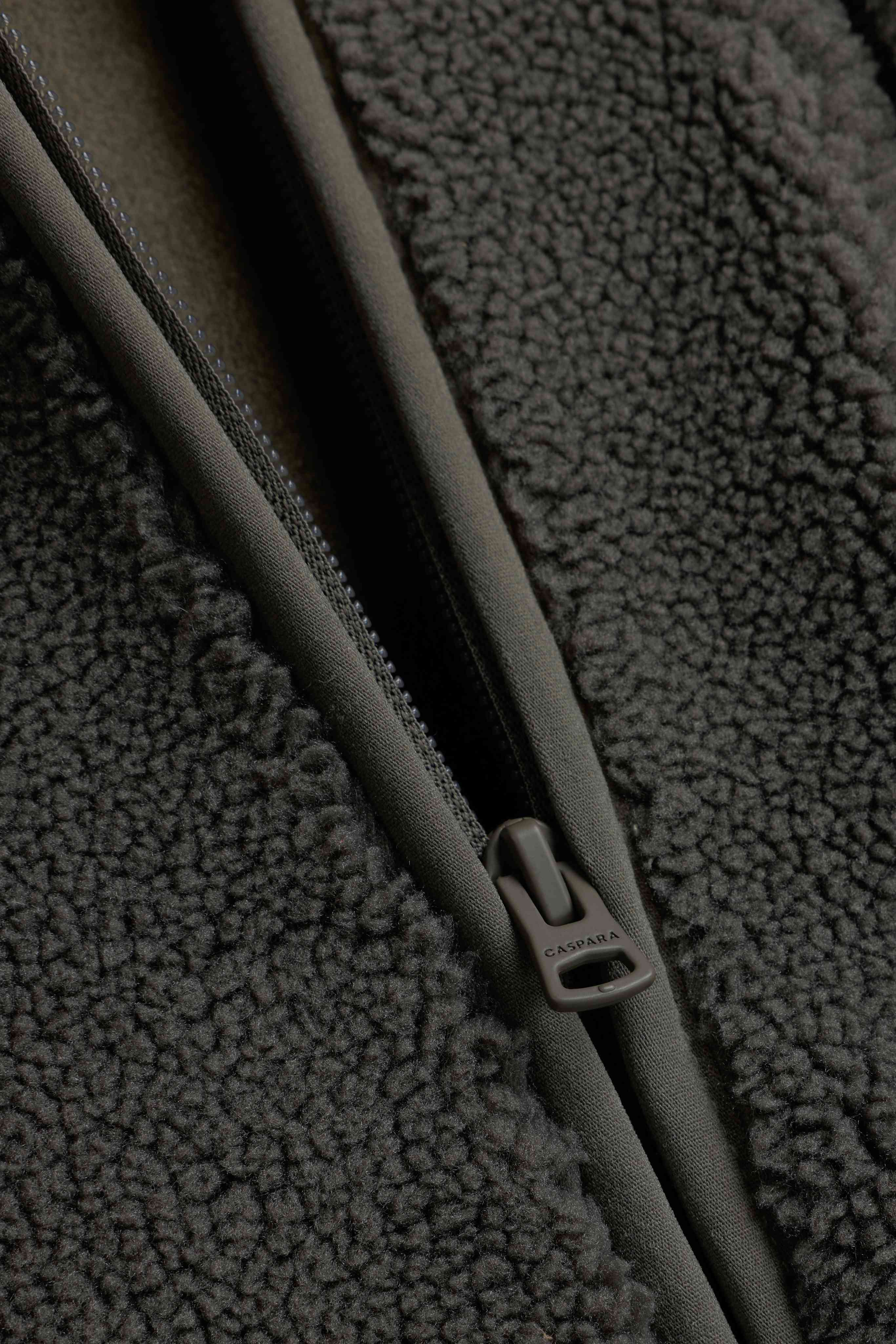 Close-up of the zipper pull and textured fleece on the khaki CASPARA Cloudfleece jacket.