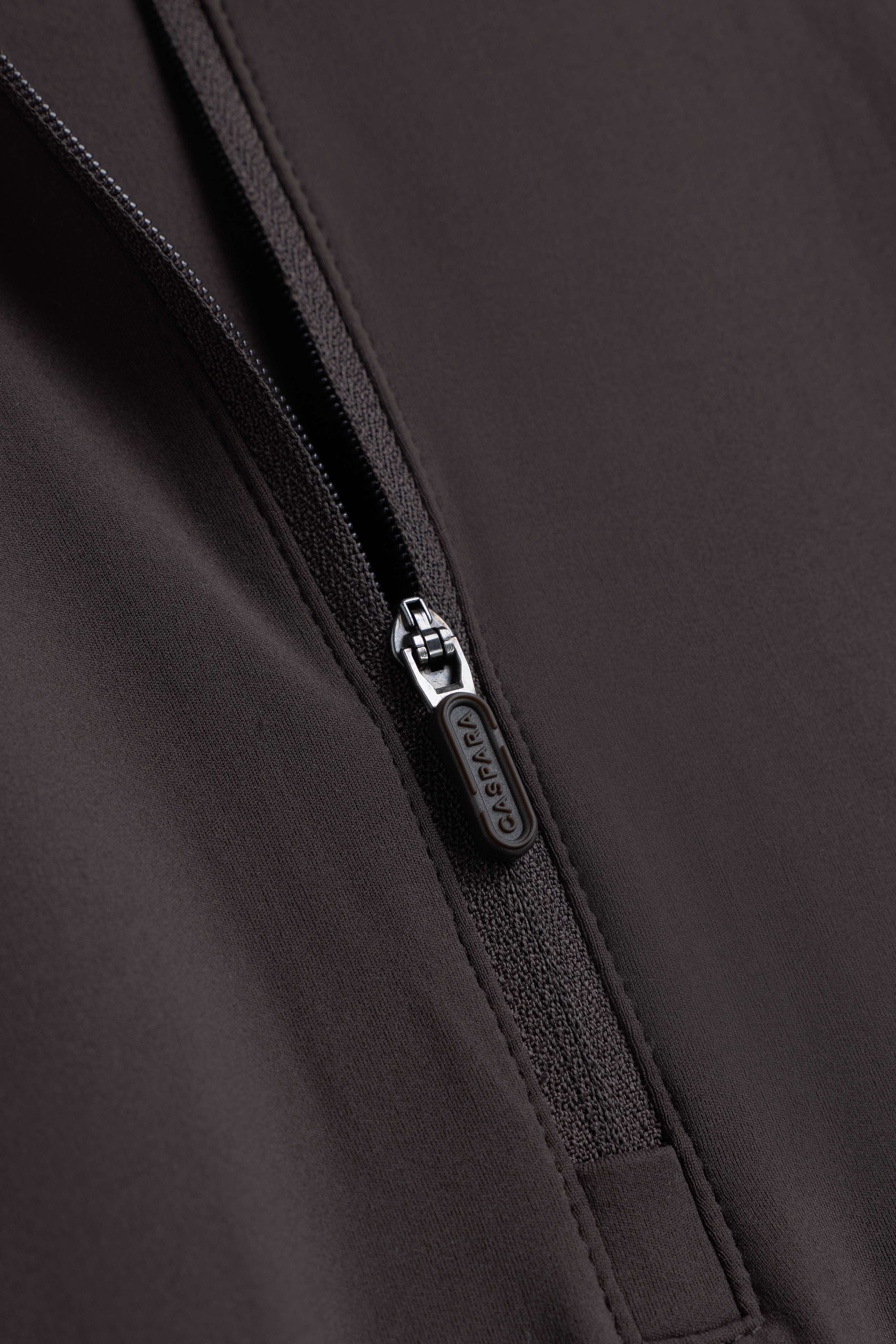 Close-up of the zipper with branded puller on the espresso CASPARA Prime Core Half Zip.
