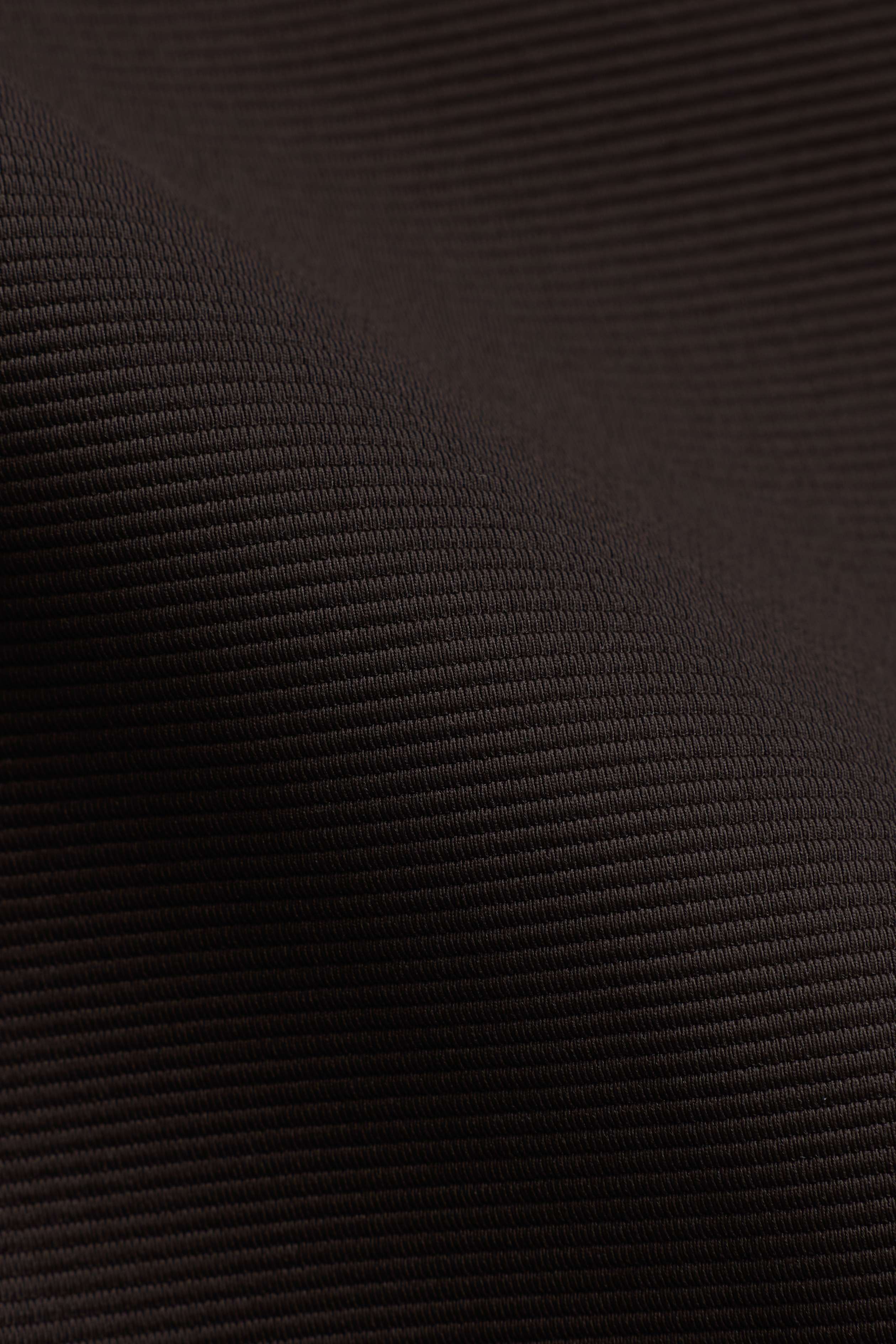 Close-up of the espresso brown textured fabric on the CASPARA Vantage Polo Tee.