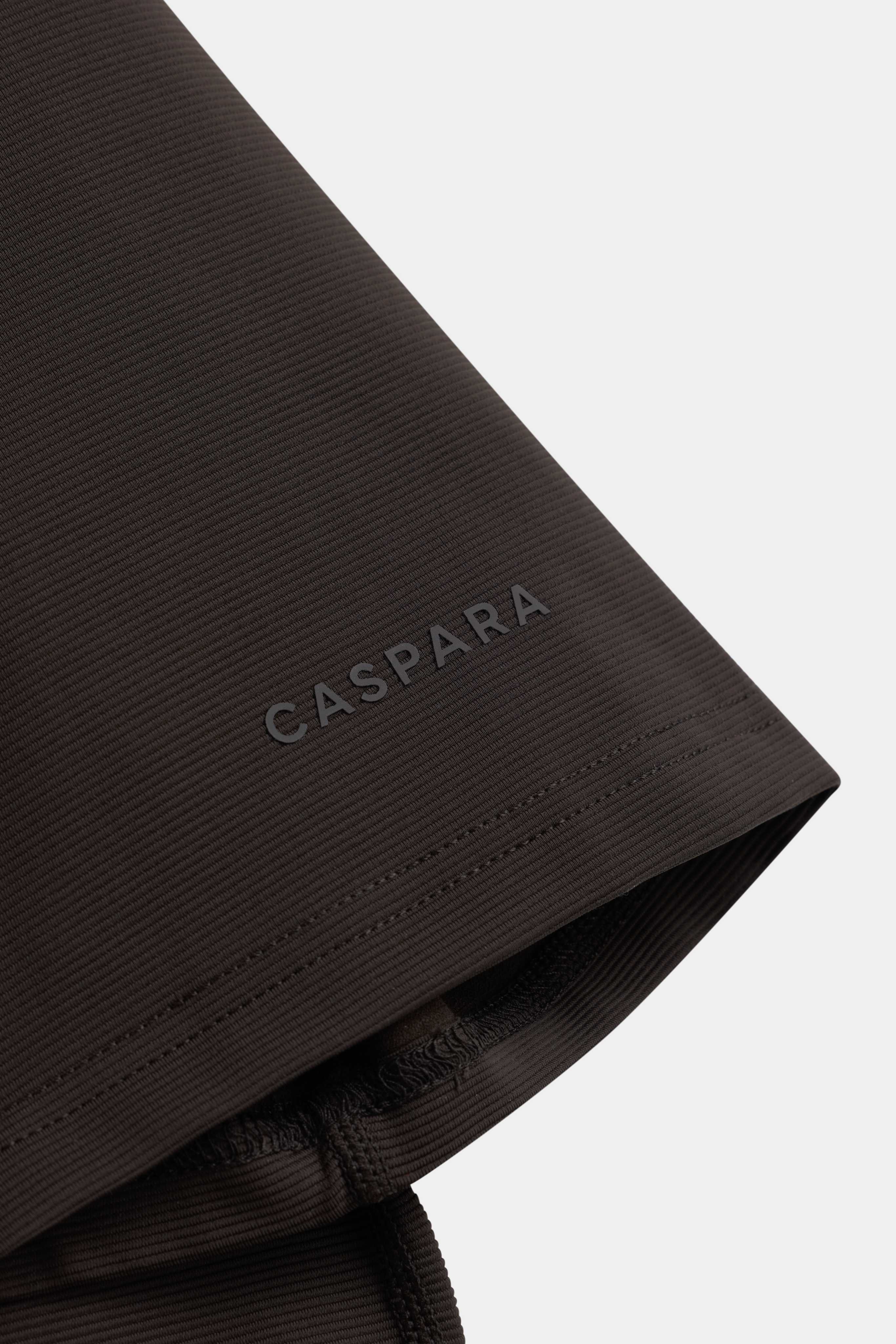 Close-up of the sleeve cuff and CASPARA logo on the espresso Vantage Polo Tee.
