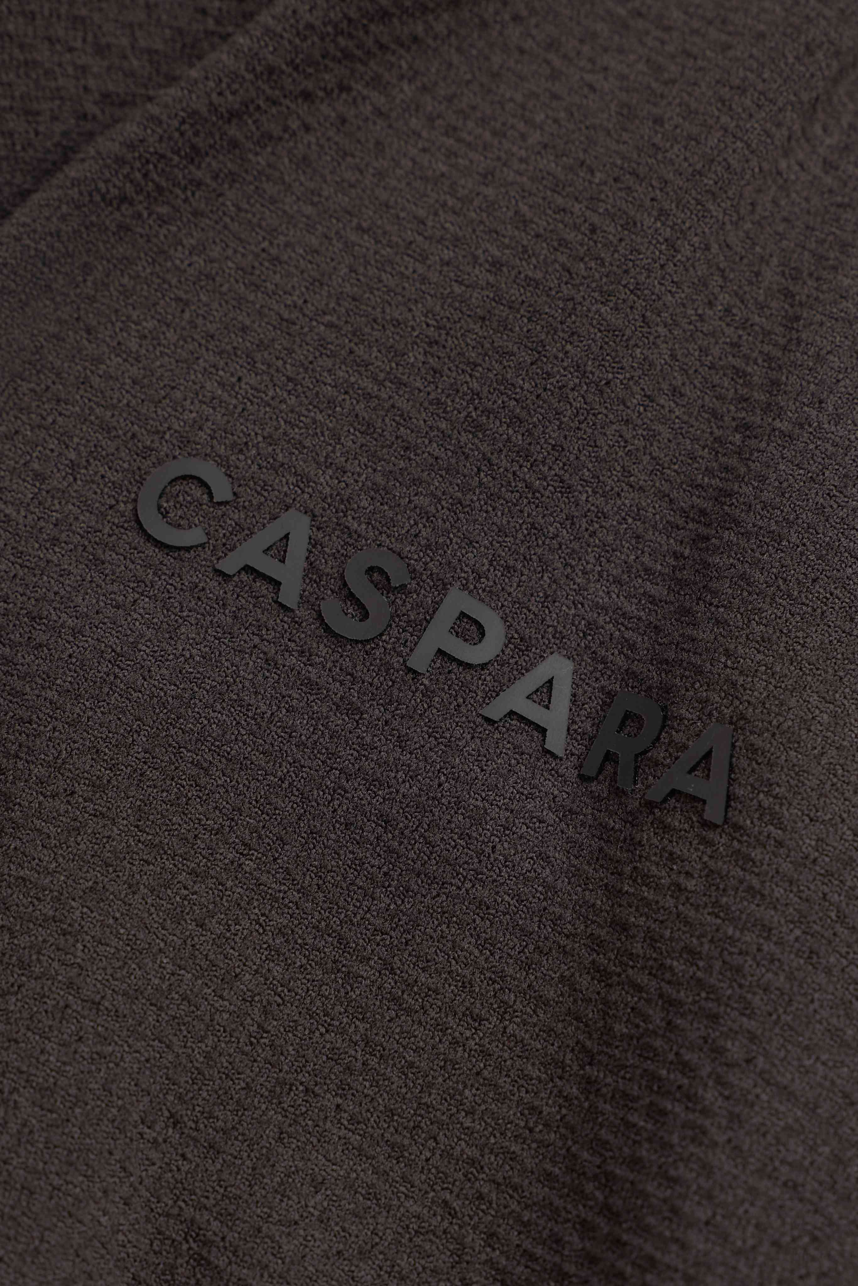 Close-up of the raised CASPARA logo on espresso textured fabric.