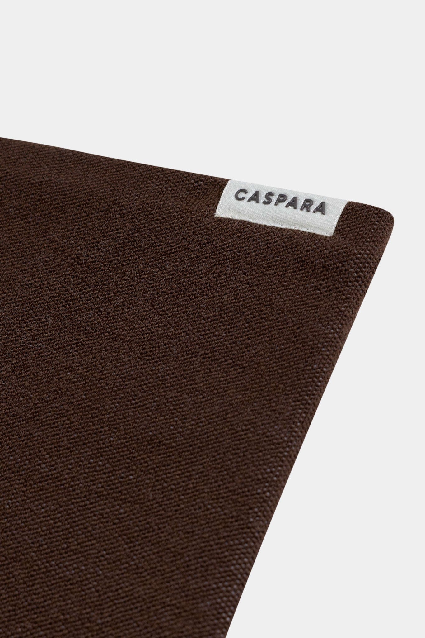 Close-up of the espresso CASPARA Classic Neckwarmer showing the knit texture and woven logo label.