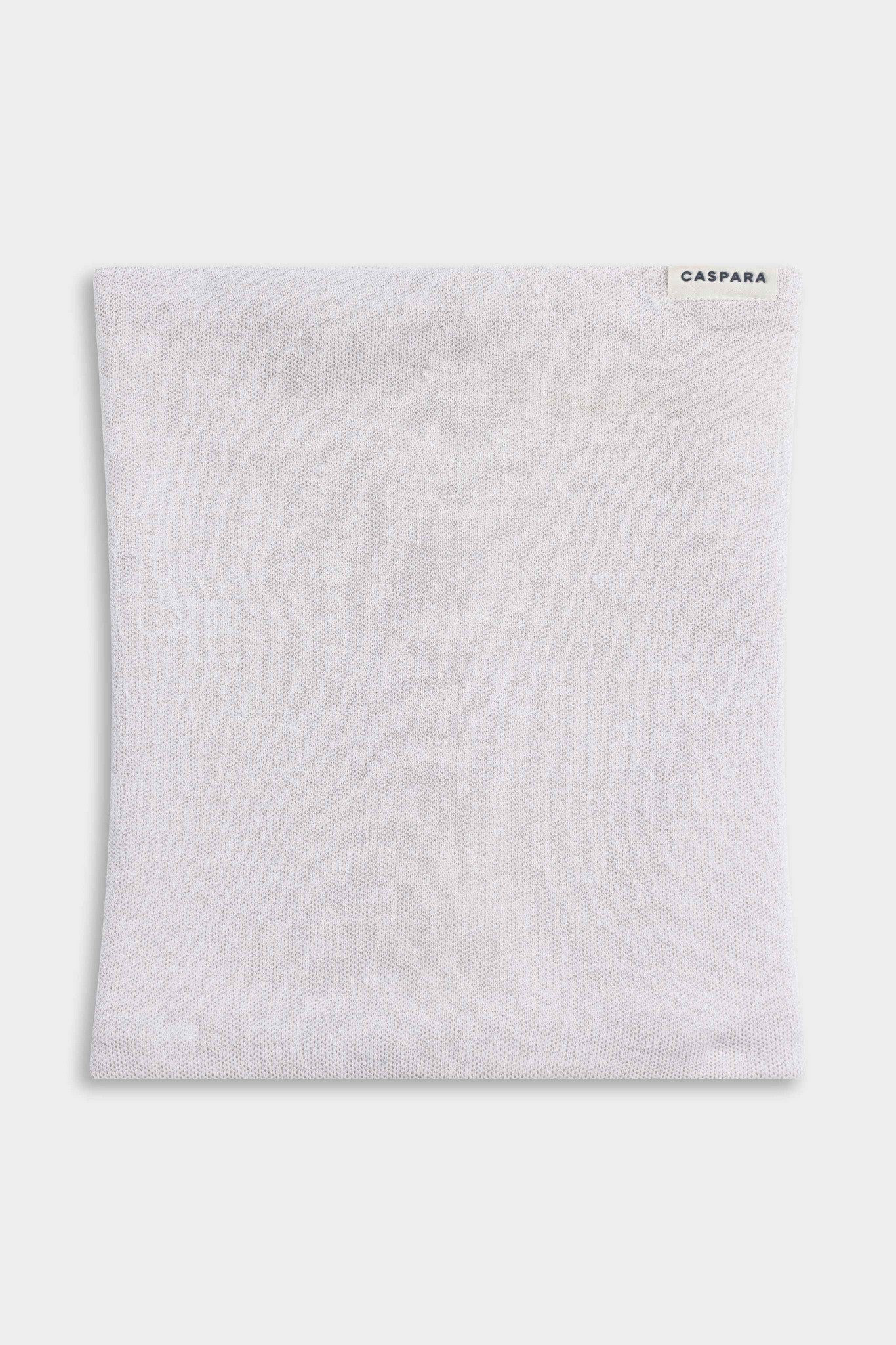 CASPARA Classic Neckwarmer in a creme knit blend laid flat on a light grey background.