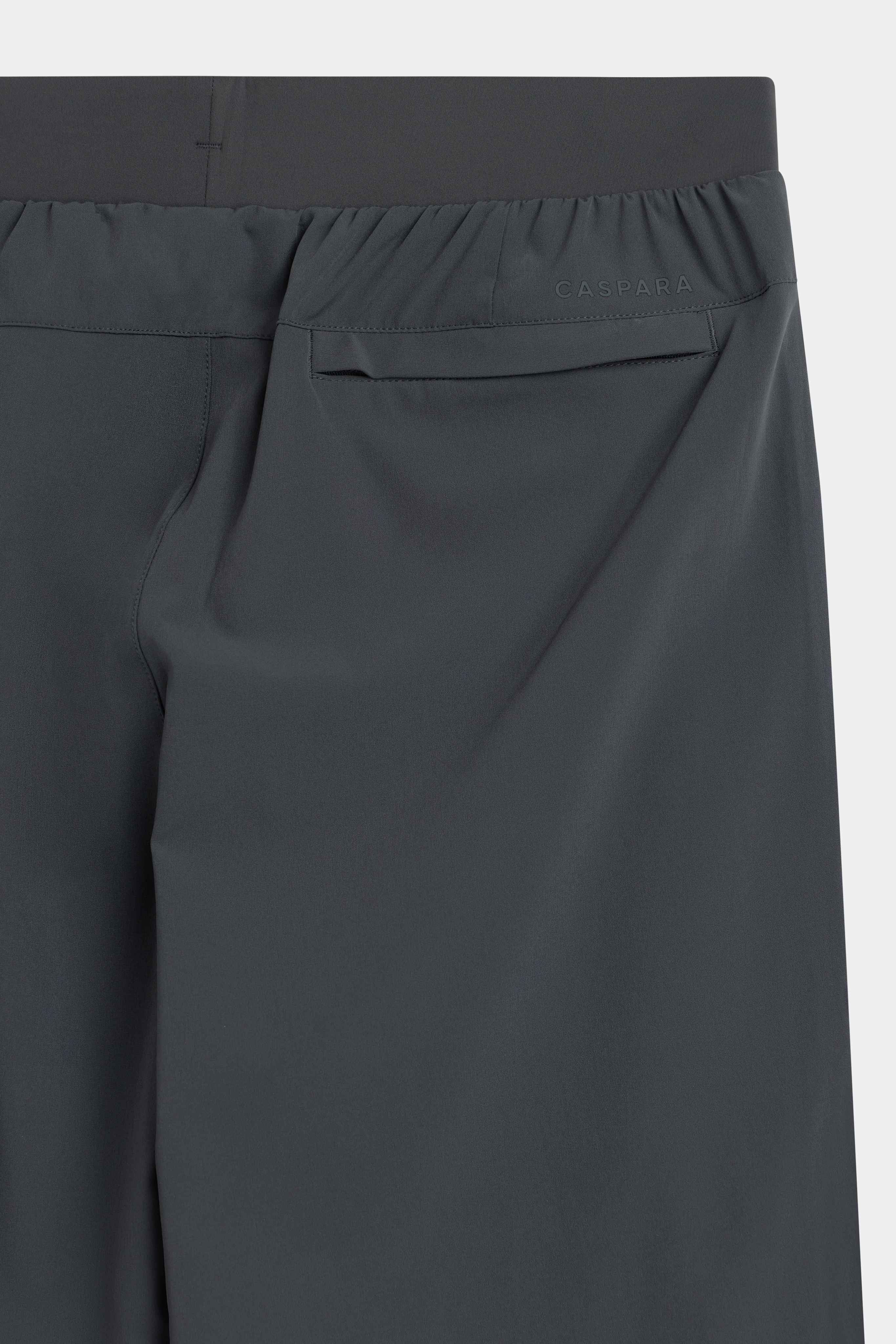 Close-up of the back pocket and elastic waistband on olive green CASPARA Prime Core pants.