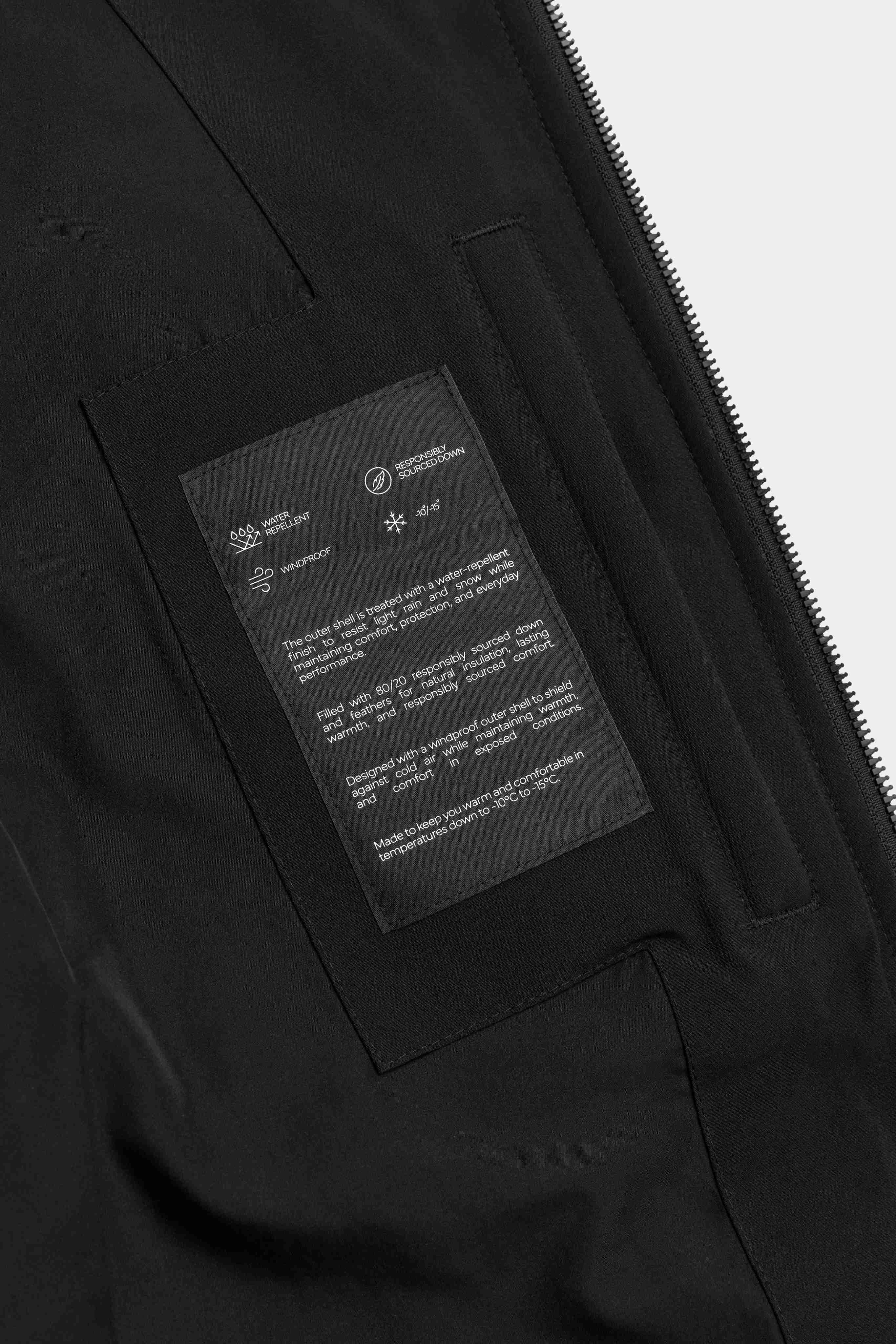Close-up of the interior pocket and technical feature patch on a black CASPARA Boreal puffer jacket.