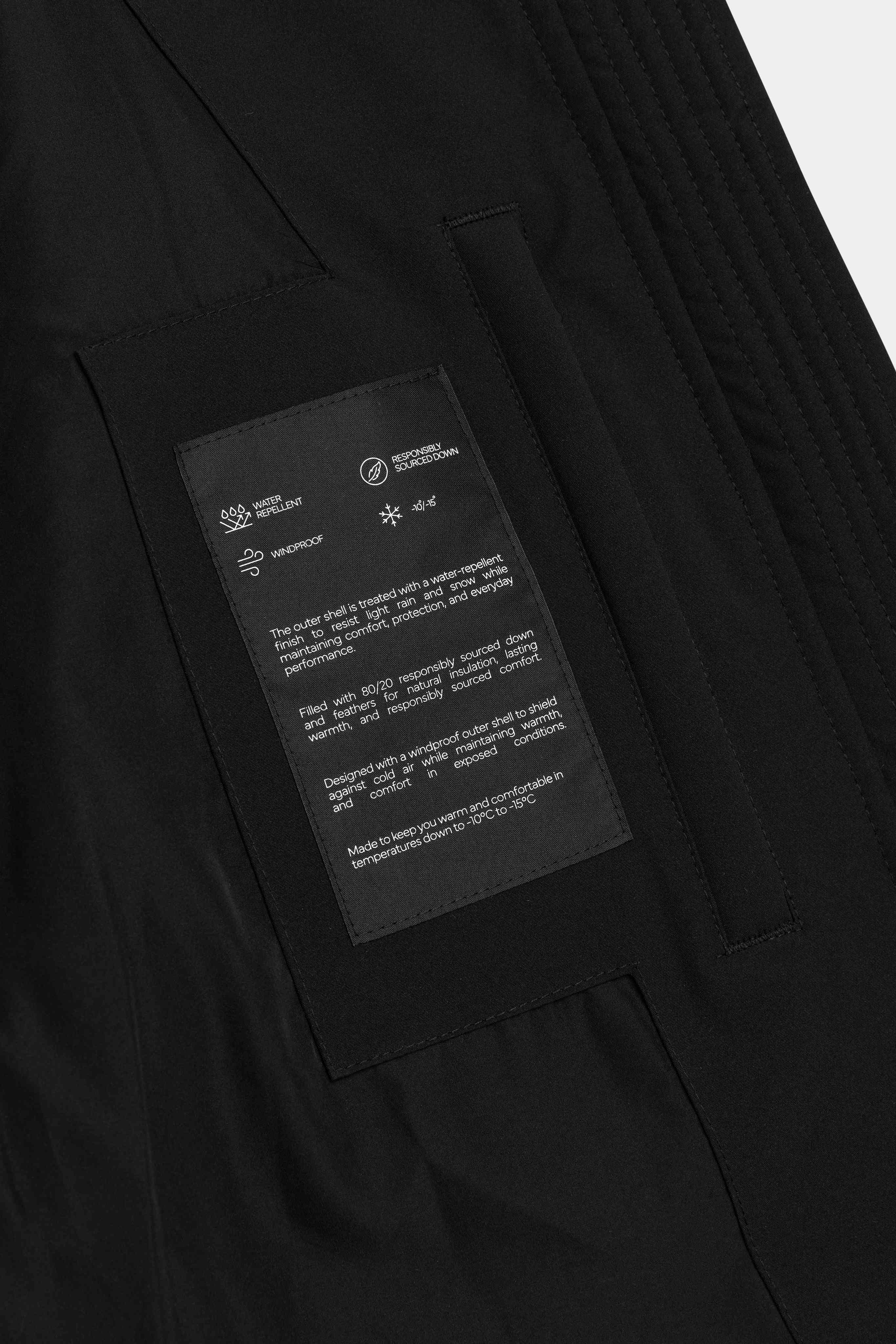 Close-up of the interior technical label on the black CASPARA Aurora Puffer Jacket.