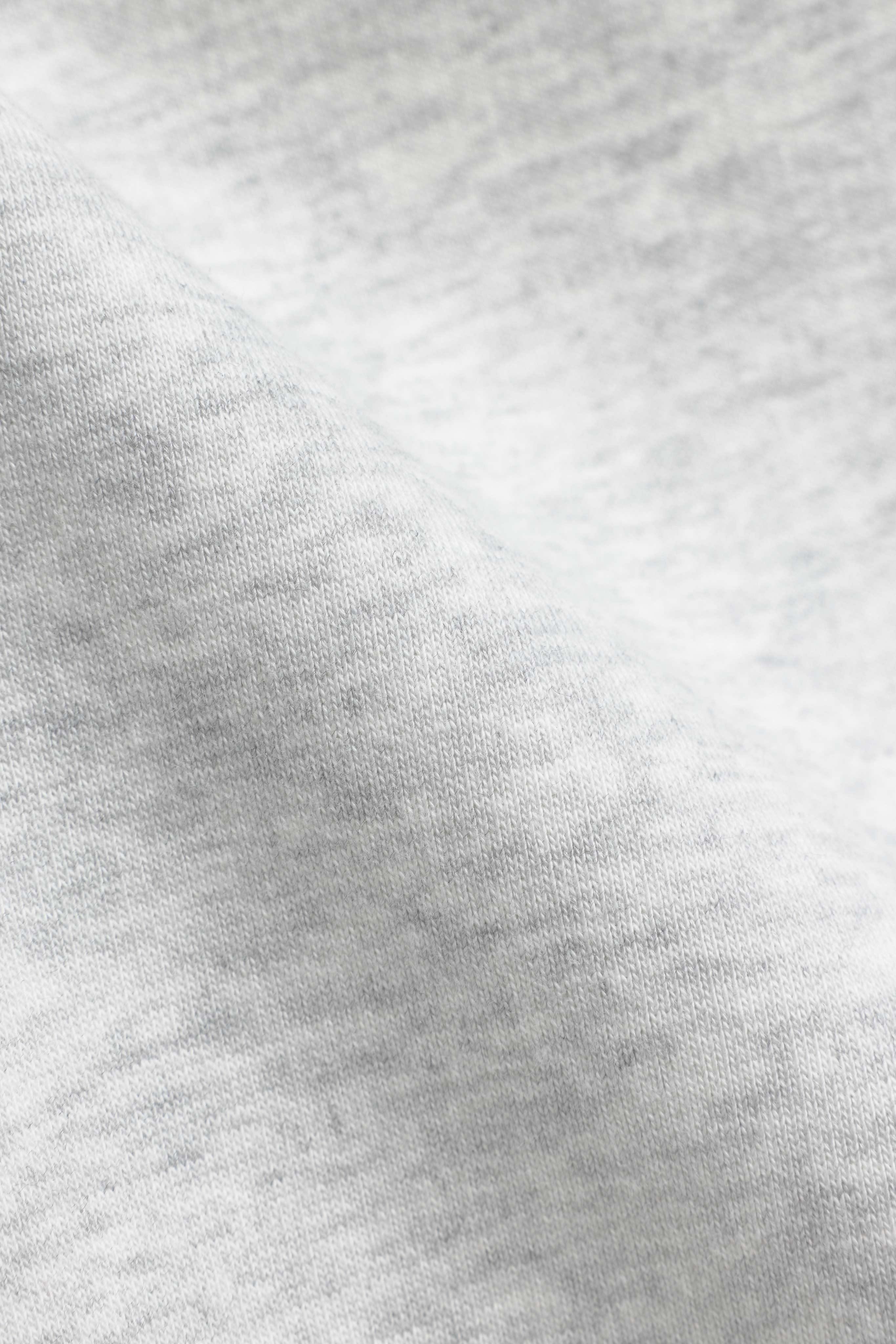 Close-up of the soft grey melange fabric texture on CASPARA sweatpants.