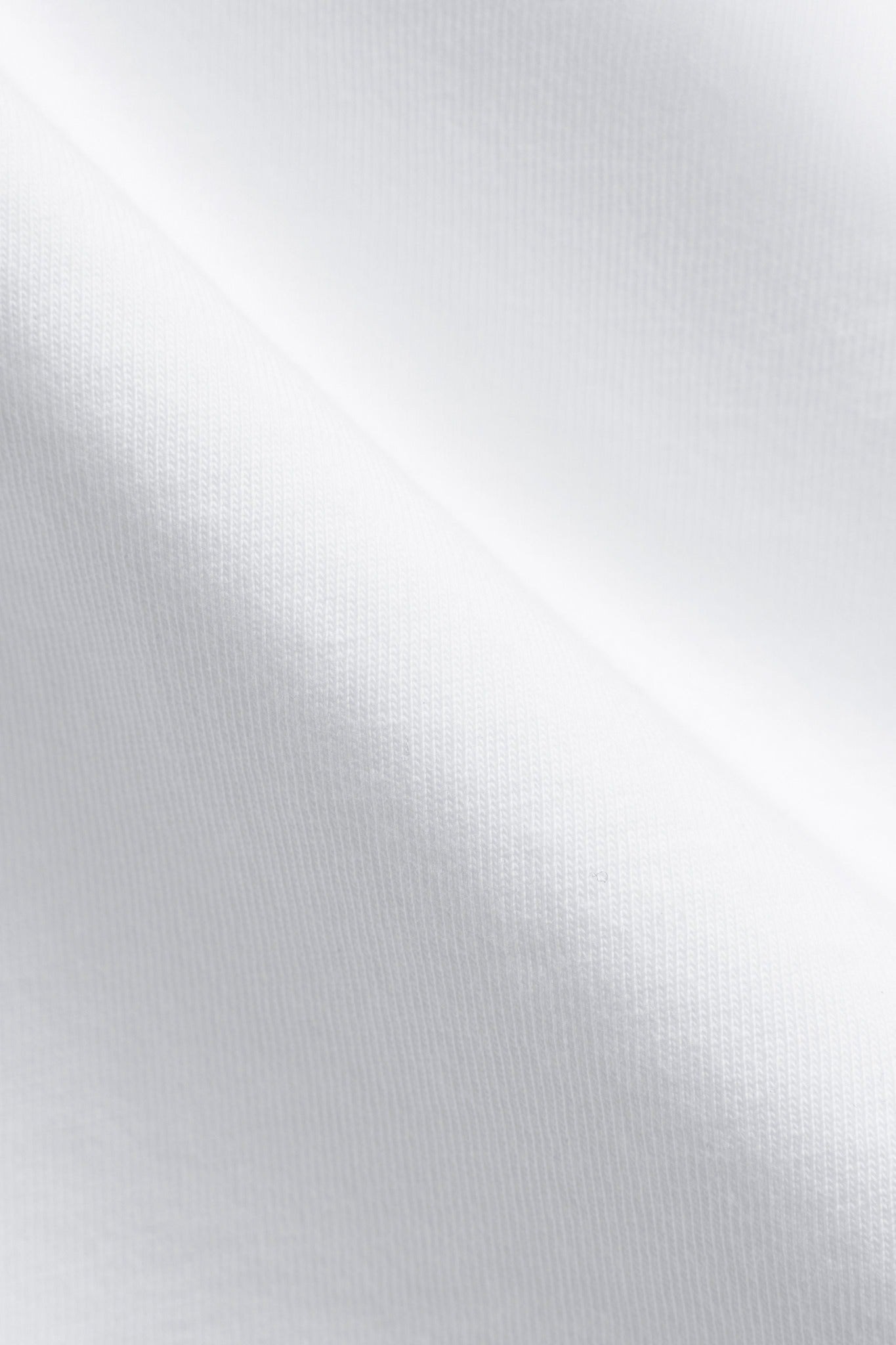 Close-up of the white organic pima cotton fabric texture on a CASPARA varsity t-shirt.