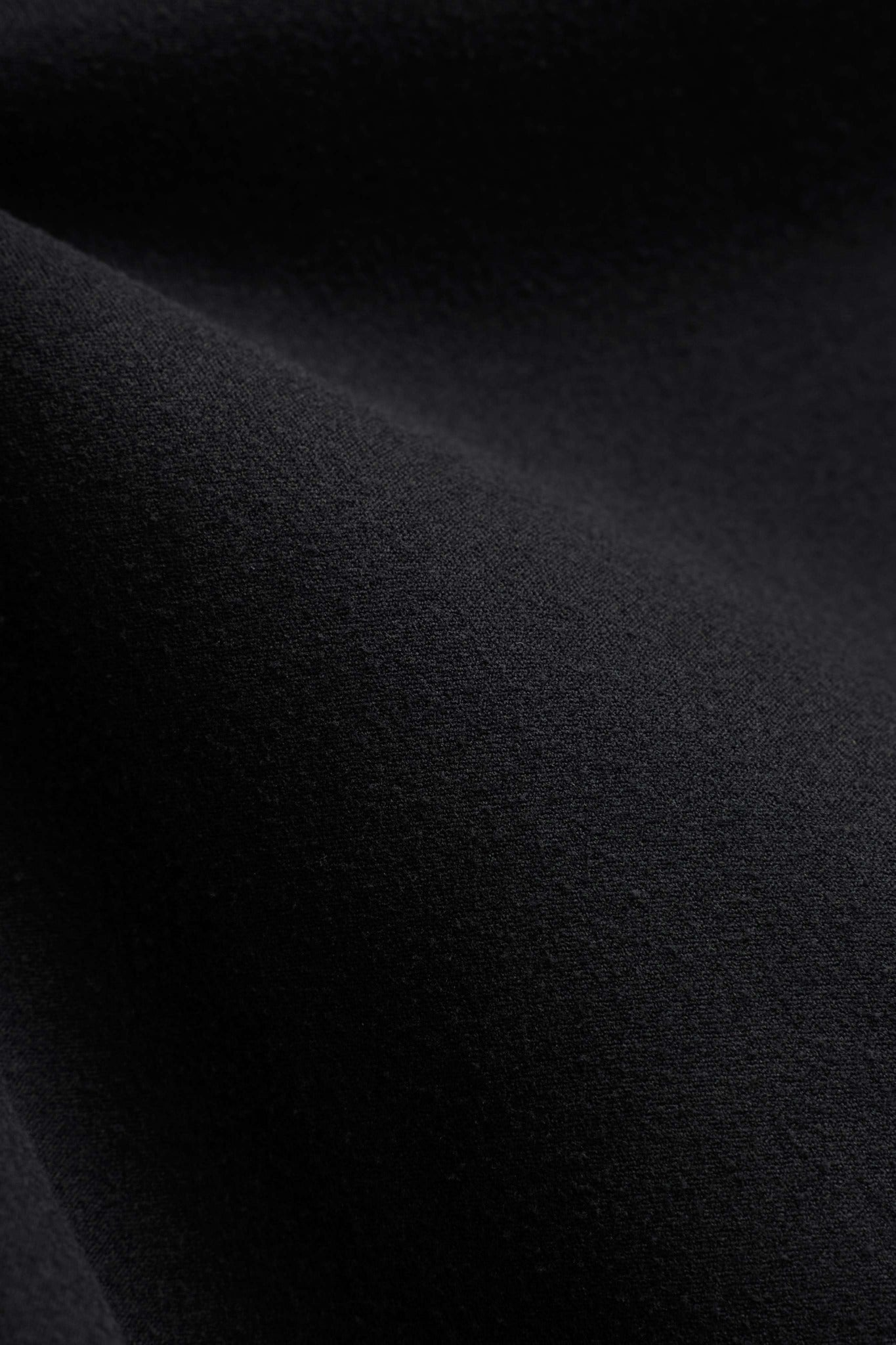 Close-up texture of the black matte Cloudform fabric on a CASPARA top.