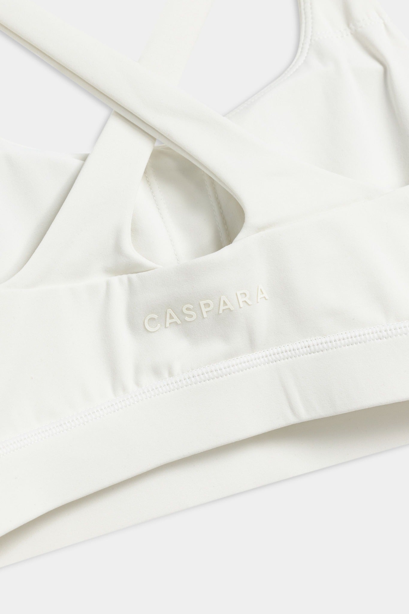 Close-up of the back crossback design and CASPARA logo on a white Cloudform sports bra.