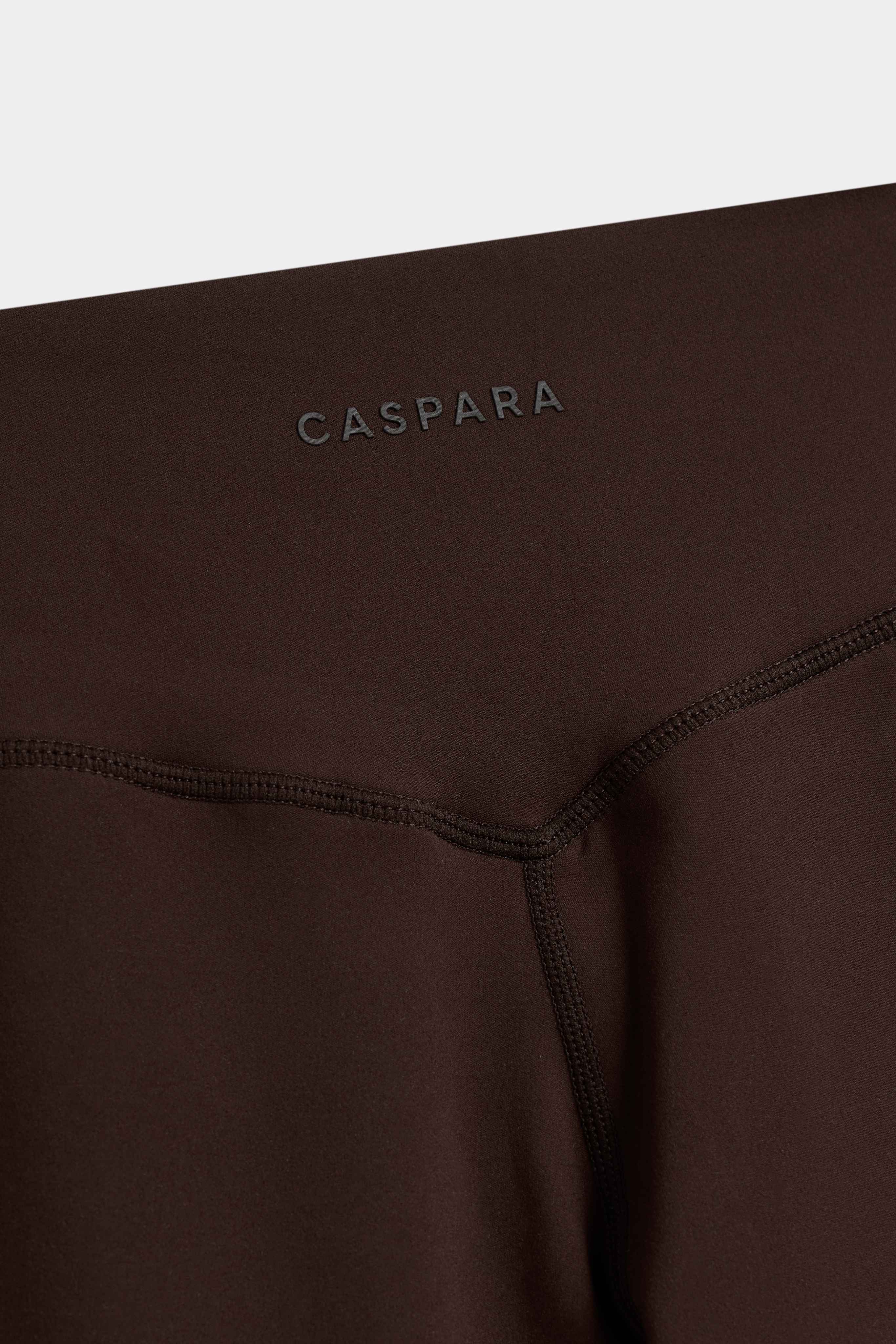 Close-up of the back waistband and logo on espresso CASPARA Cloudform yoga pants.