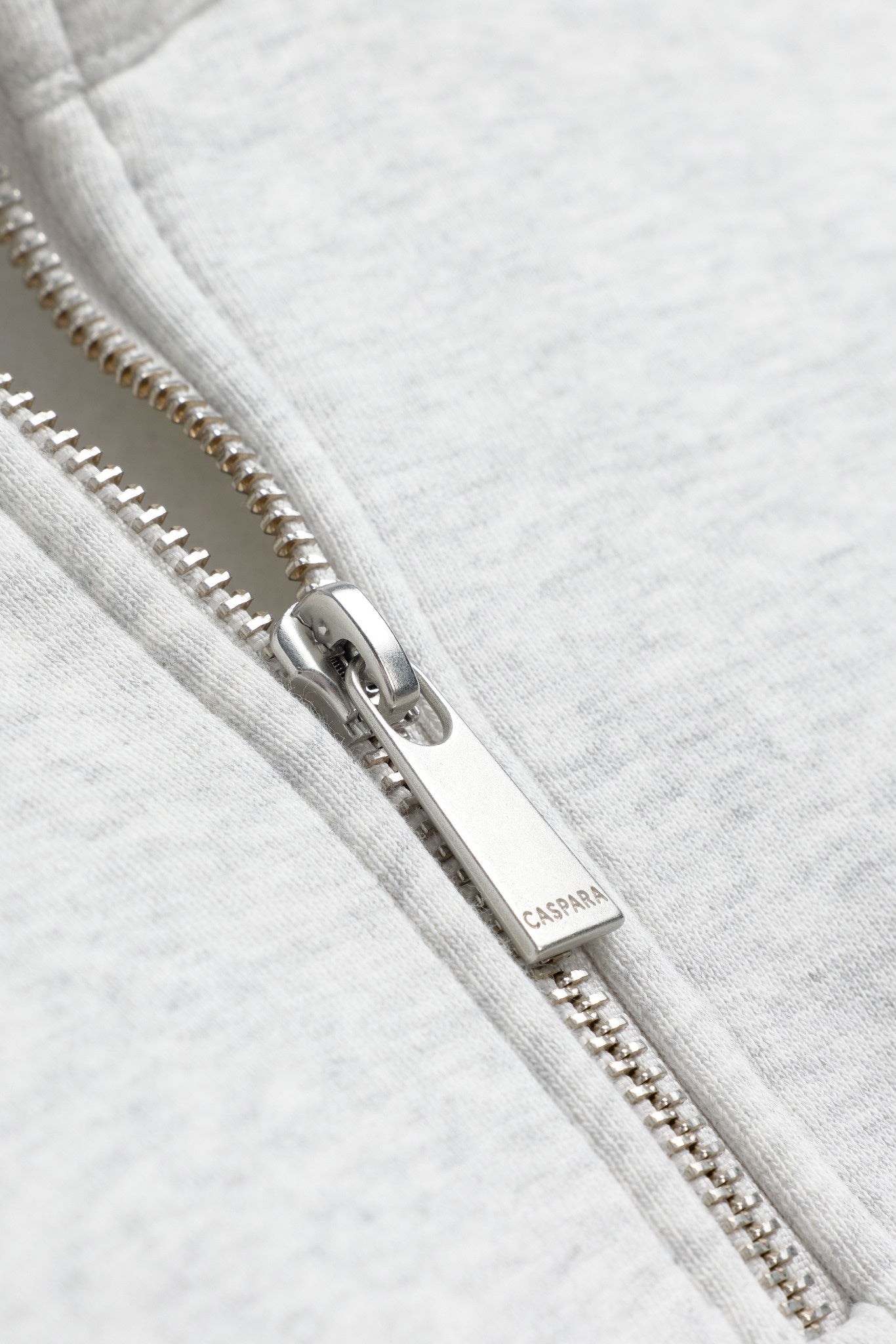 Close-up of a silver metal CASPARA zipper pull on a grey melange quarter-zip sweatshirt.