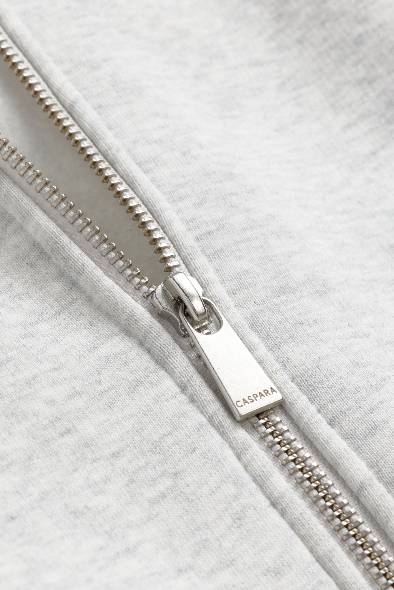Close-up of the silver zipper pull with engraved CASPARA logo on a grey melange sweatshirt.