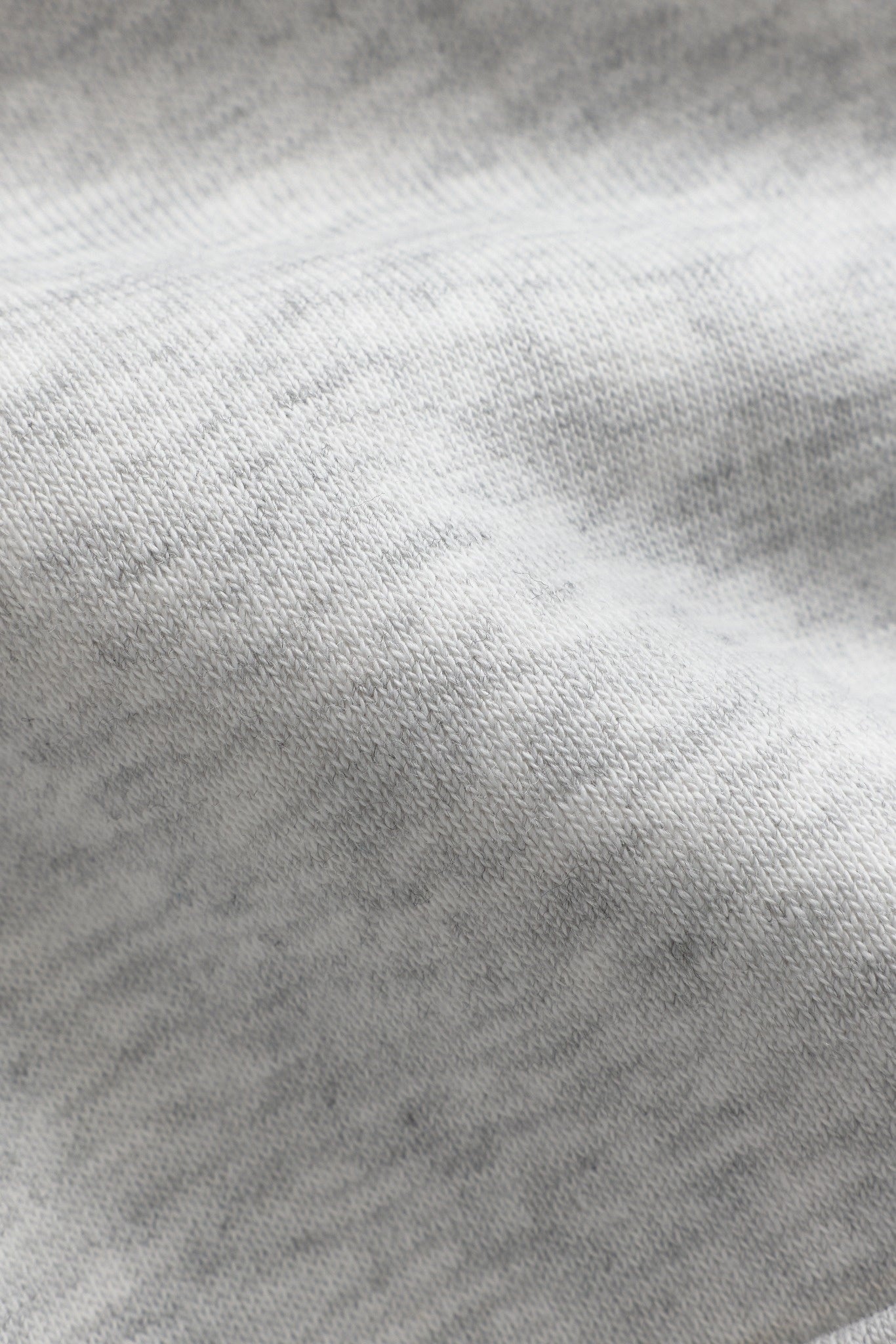Close-up texture of grey melange cotton blend fabric on the CASPARA All-Star hoodie.