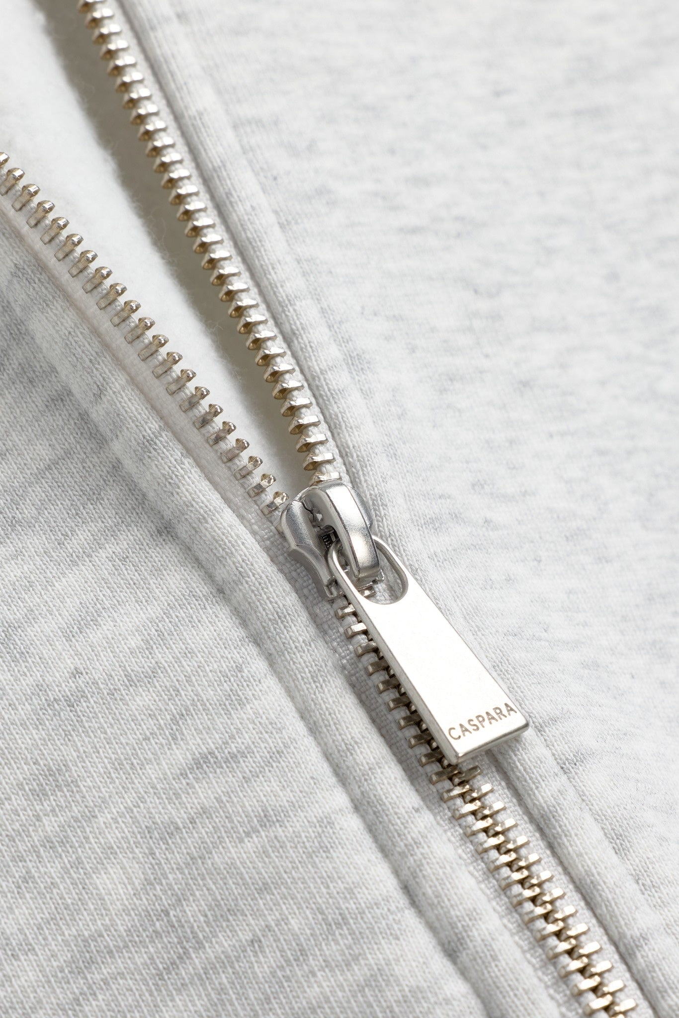 Close-up of a silver engraved CASPARA zipper on a grey melange zip hoodie.