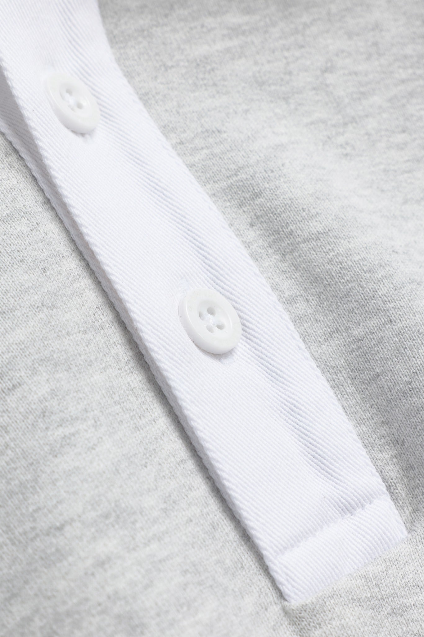 Close-up of the white buttoned placket on a grey melange CASPARA rugby shirt.