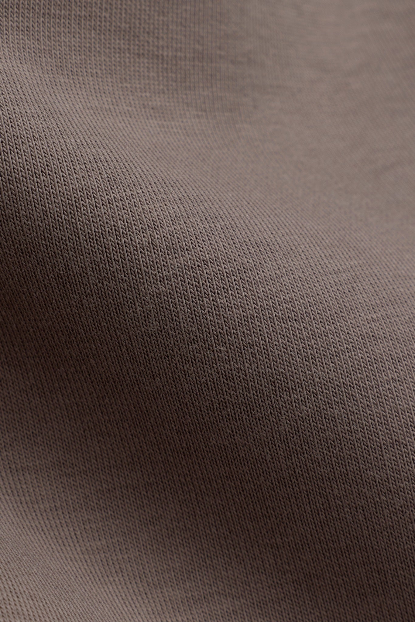 Close-up view of the walnut cotton-blend knit fabric texture on CASPARA All-Star pants.