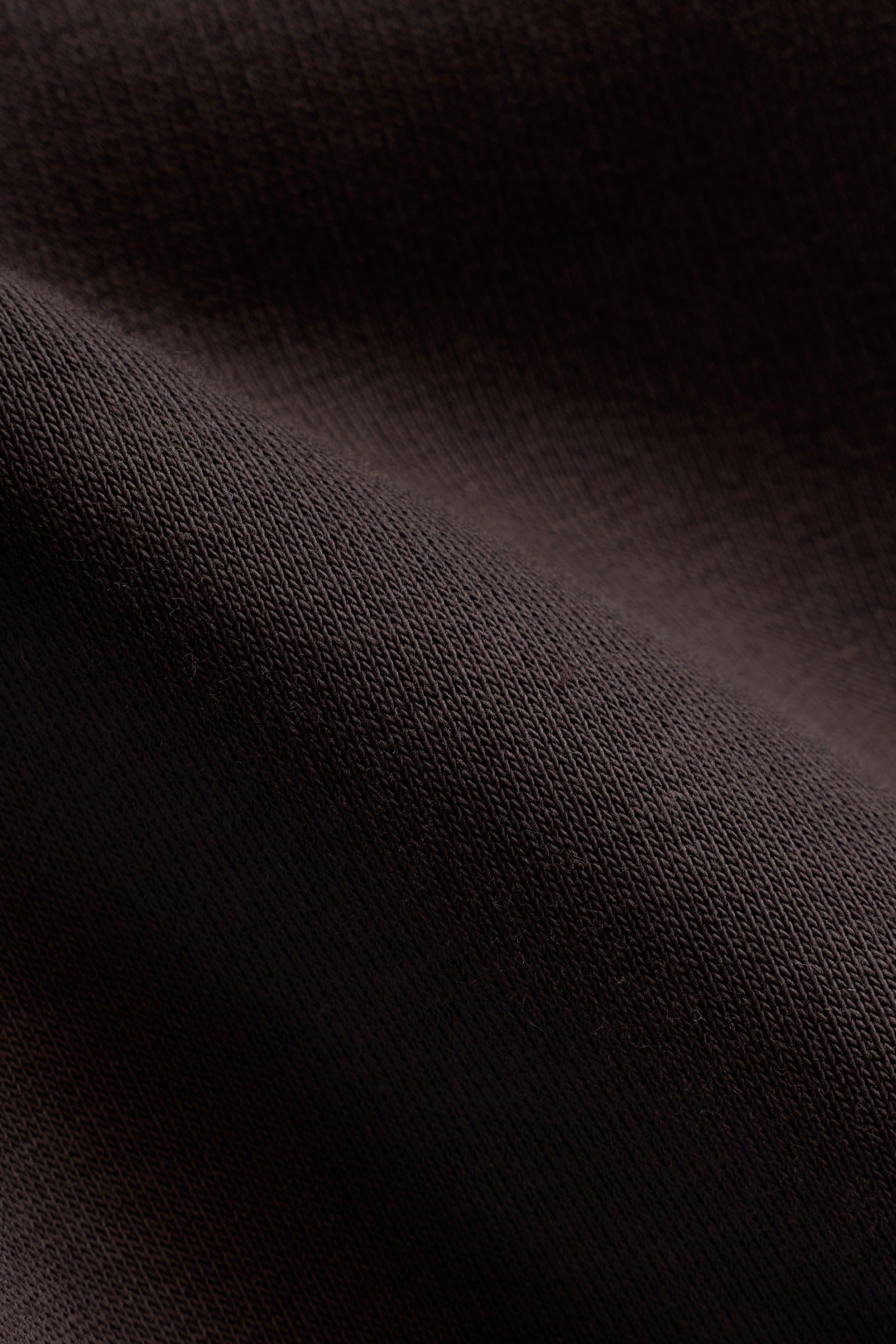 Close-up texture of espresso brown cotton fabric on the CASPARA All-Star hoodie.