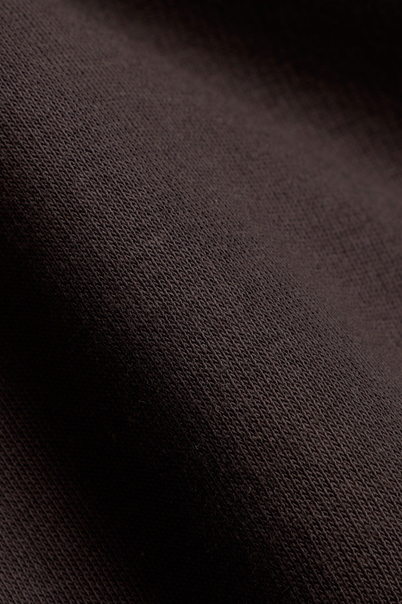 Close-up of espresso brown cotton fabric texture on a CASPARA sweatshirt.