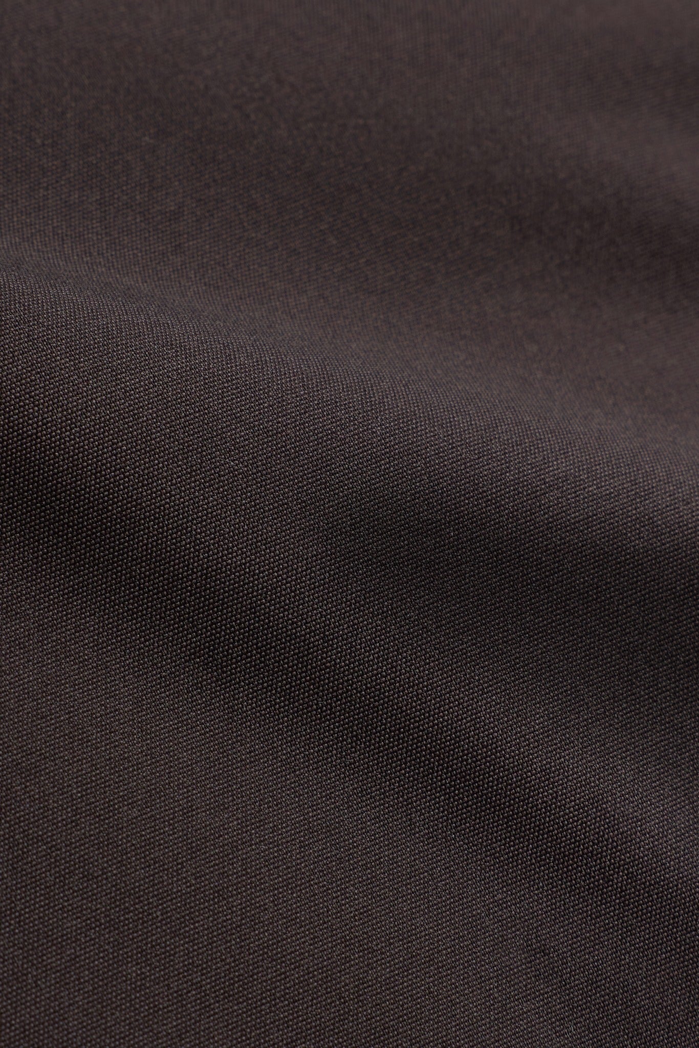 Close-up of the textured espresso brown outer fabric on the CASPARA Aurora puffer vest.